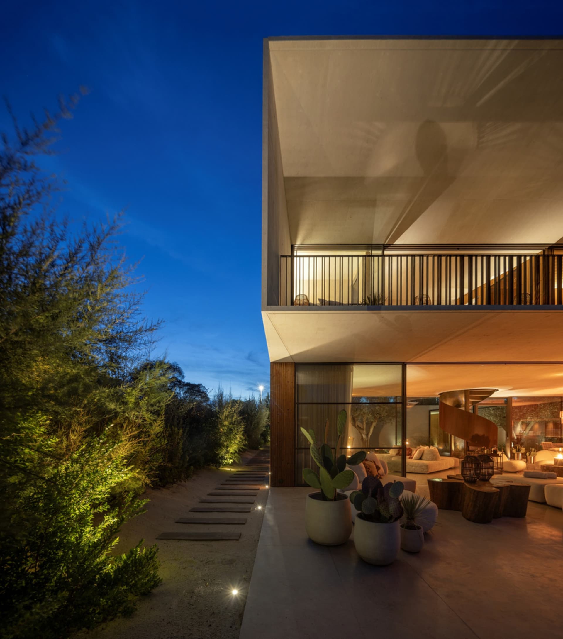Modern residential exterior with concrete structure and illumination at dusk.