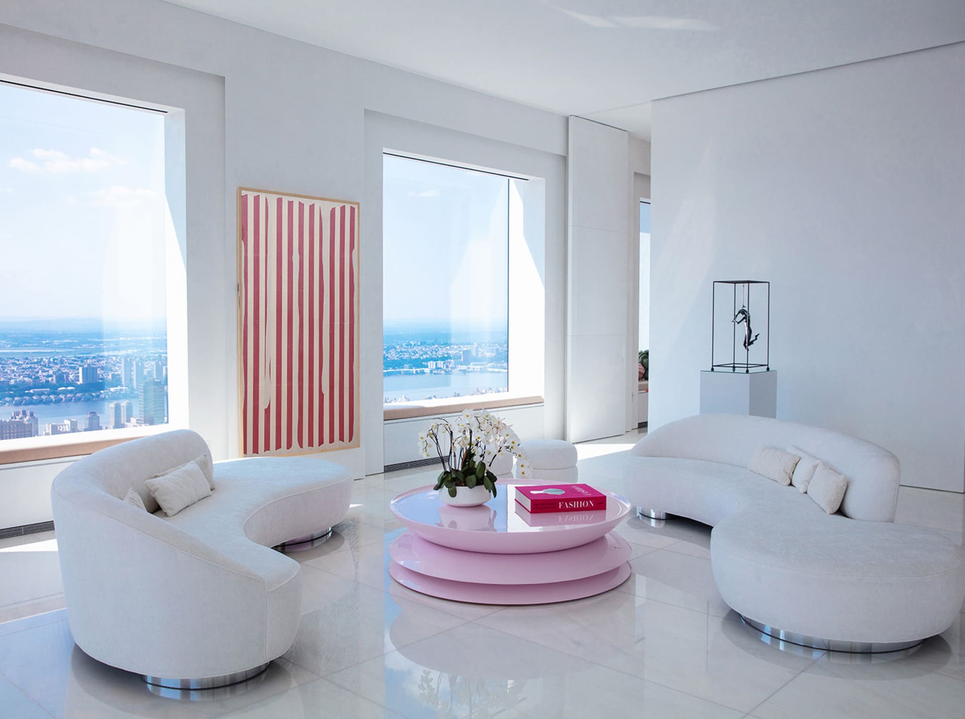 A modern minimalist living room featuring a minimalist design aesthetic, with white curved sofas, a glass and metal coffee ta