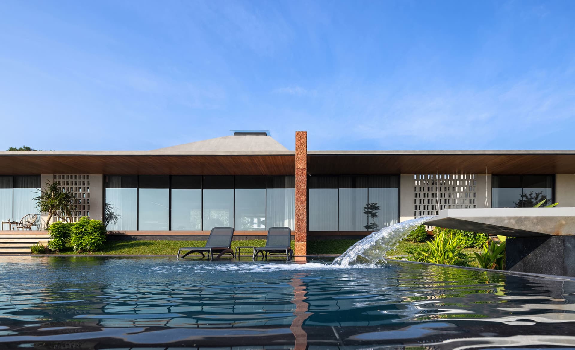 A modern residential exterior featuring a sleek, contemporary design with a mix of concrete and glass materials, set against