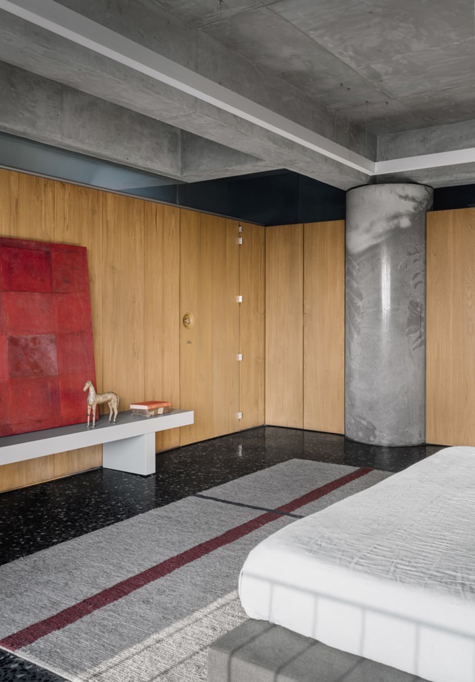 Close-up of a modern bedroom with a concrete ceiling, concrete floor, and wooden walls.
