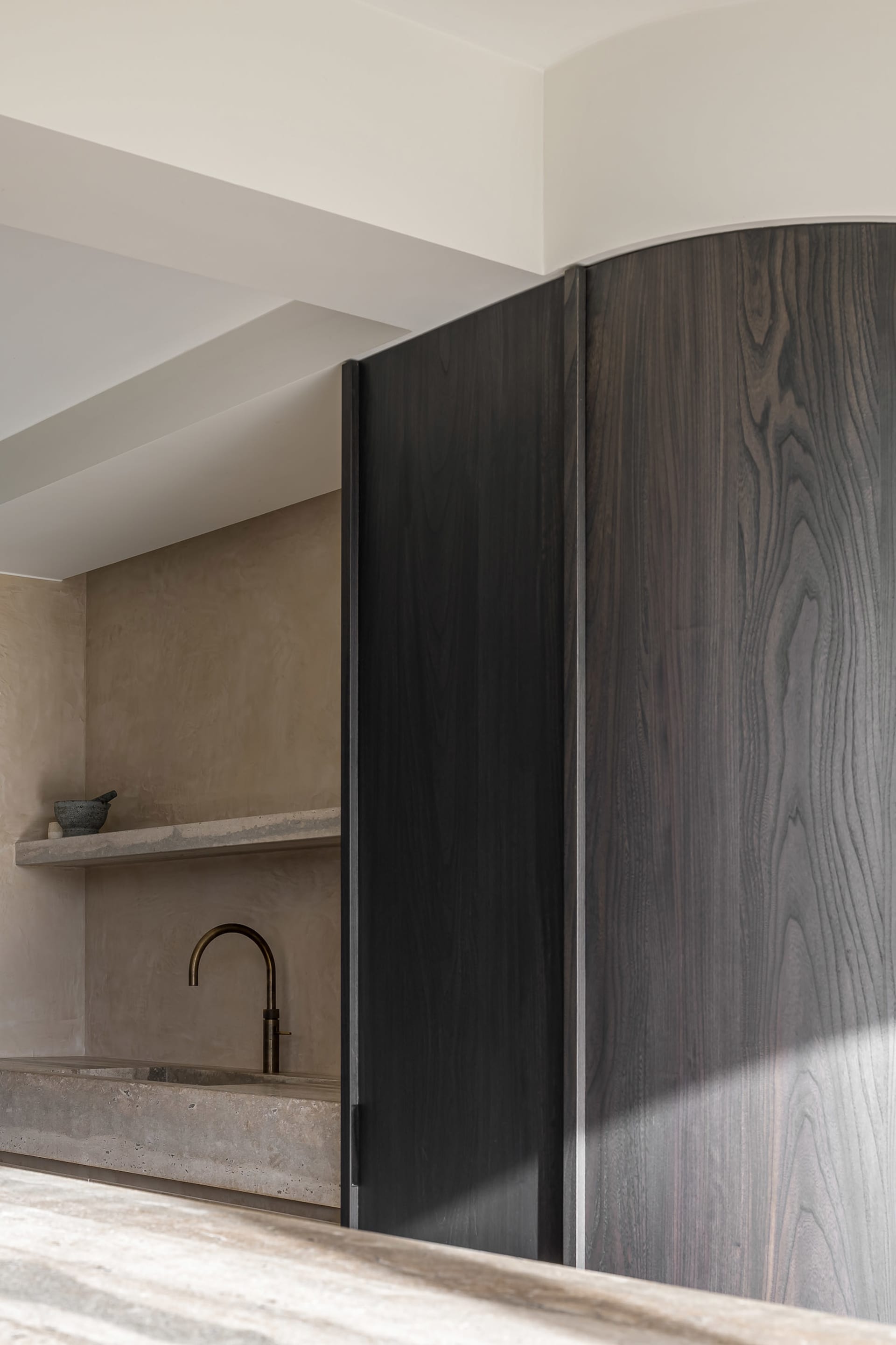 A minimalist interior with dark wooden cabinetry and a concrete countertop.
