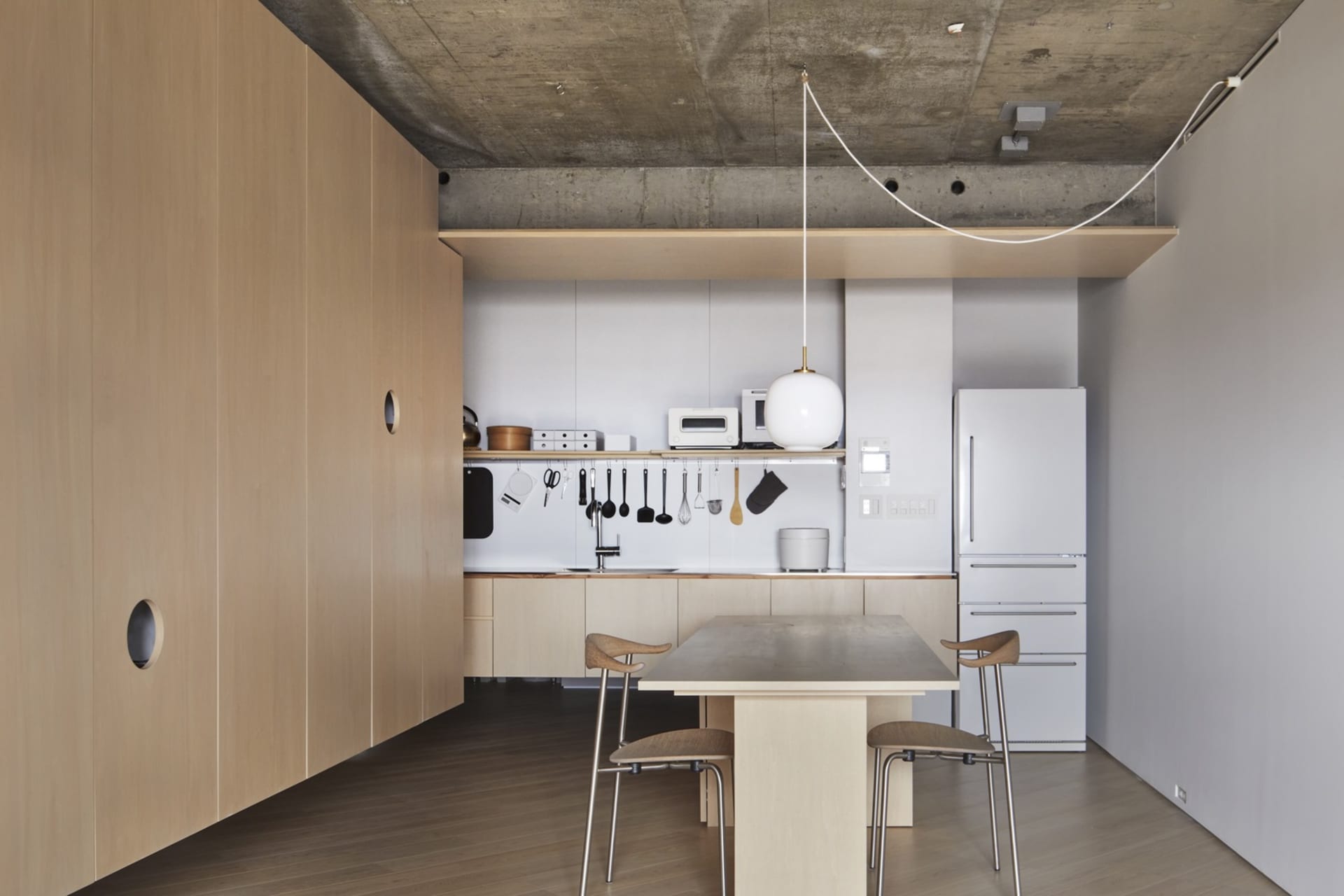 Modern minimalist kitchen with concrete countertops, wooden cabinets, and metal fixtures.