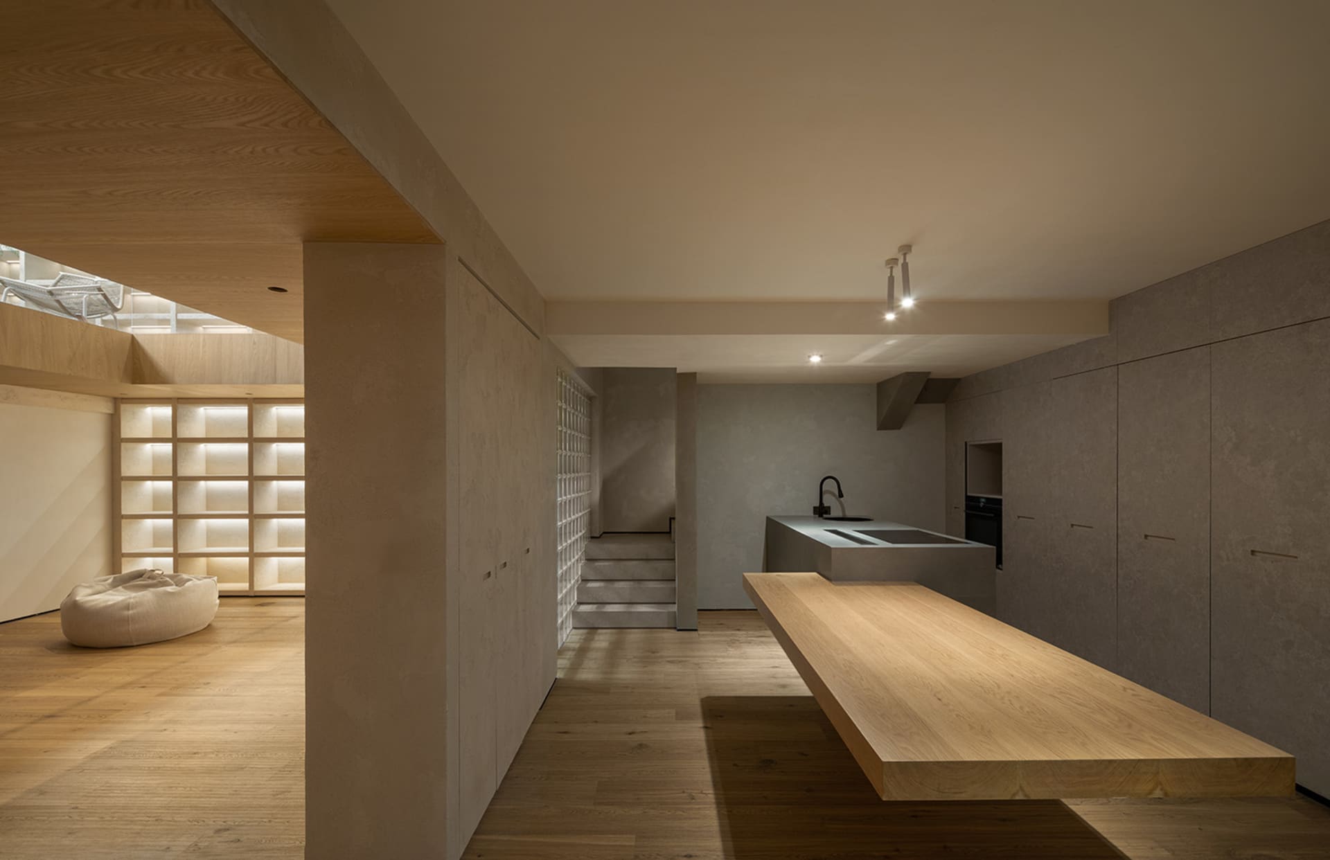 A modern minimalist kitchen with solid wooden countertops and cabinets, illuminated by soft under-cabinet lighting, and featu