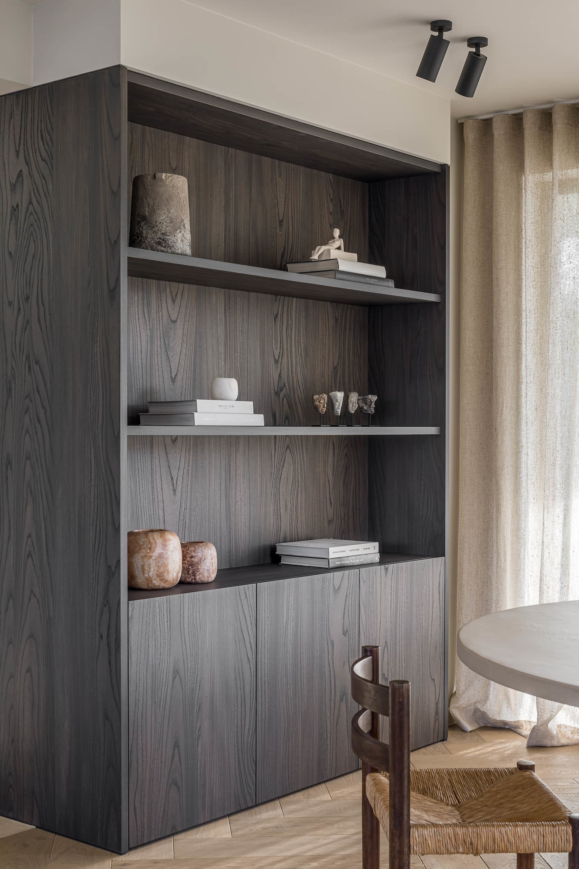A modern bookshelf made of dark wood with decorative items on the shelves.