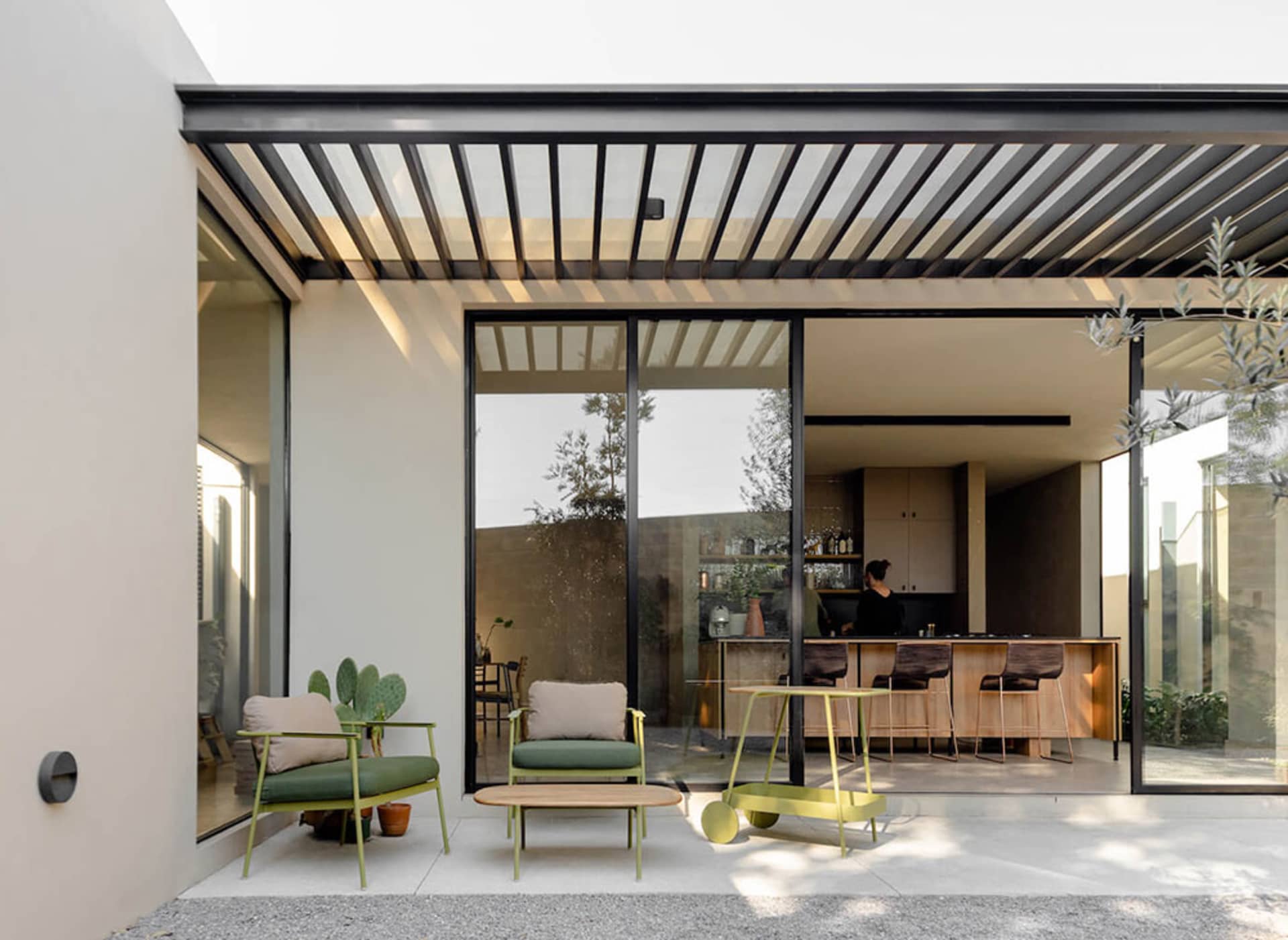 Modern minimalist residential interior featuring exposed steel beams, glass walls, concrete flooring, and wood accents.