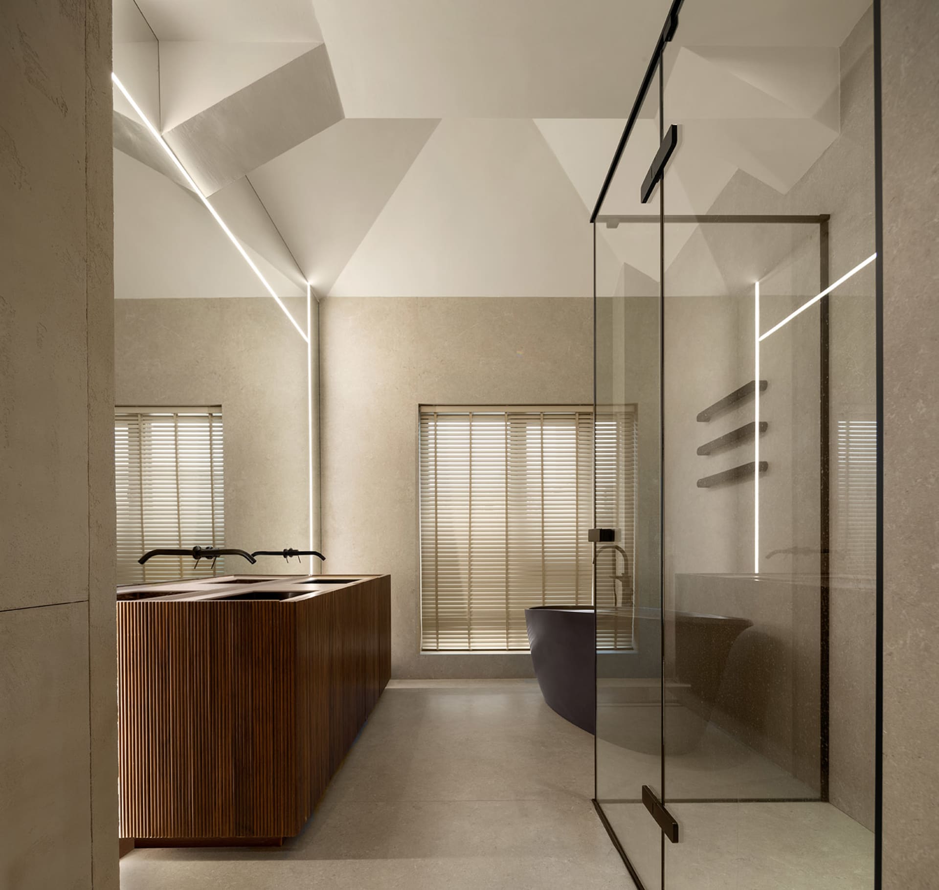 Photograph of a minimalist bathroom with concrete walls and a glass shower enclosure.