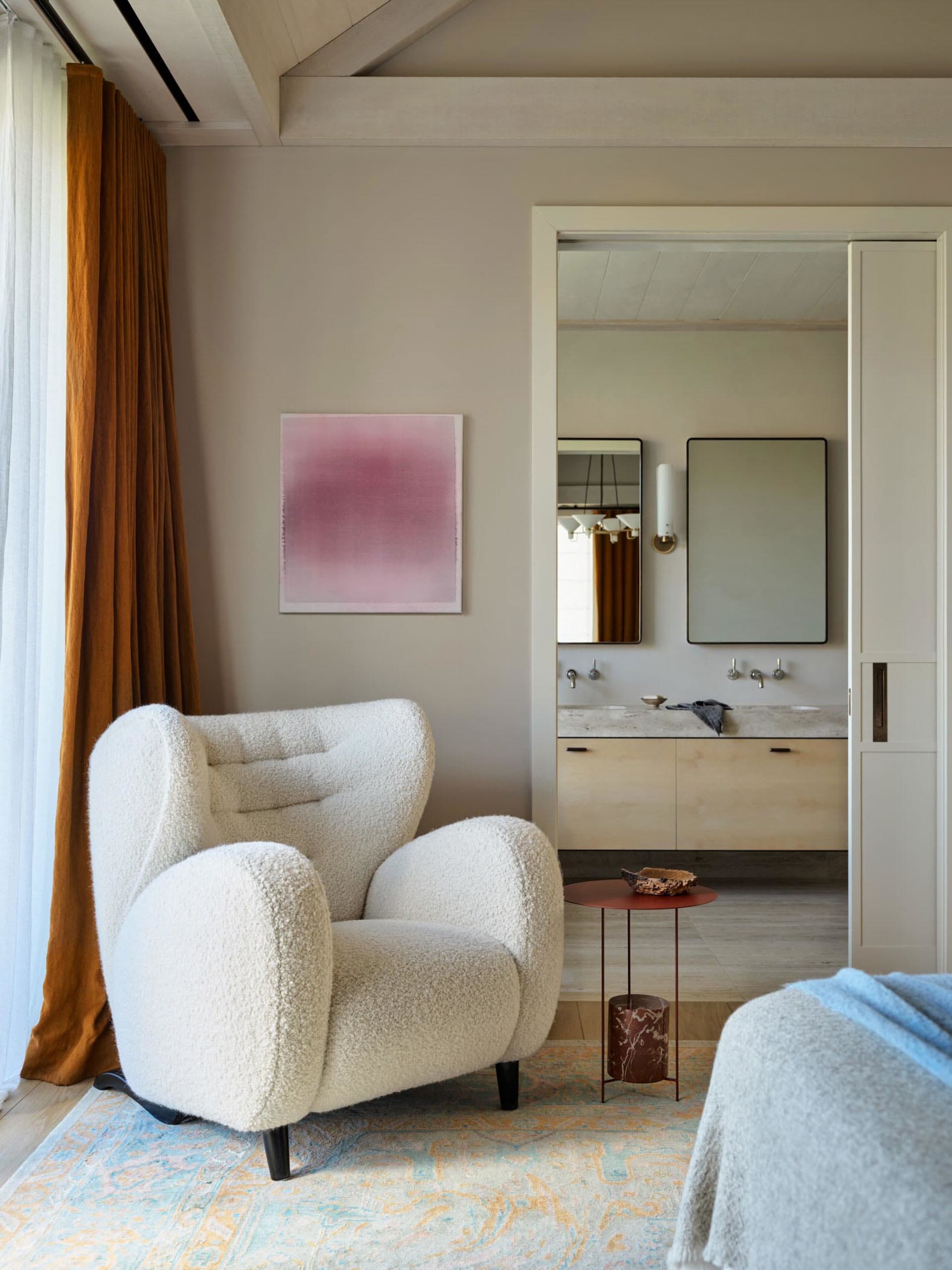 A modern living room featuring a comfortable white wingback chair with a traditional texture, a red side table, and a blue bl