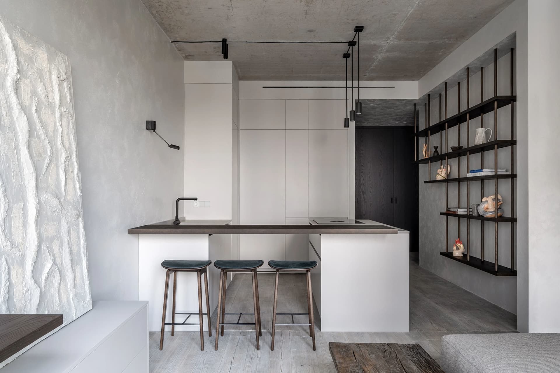 Modern minimalist kitchen featuring concrete countertops and wooden stools.