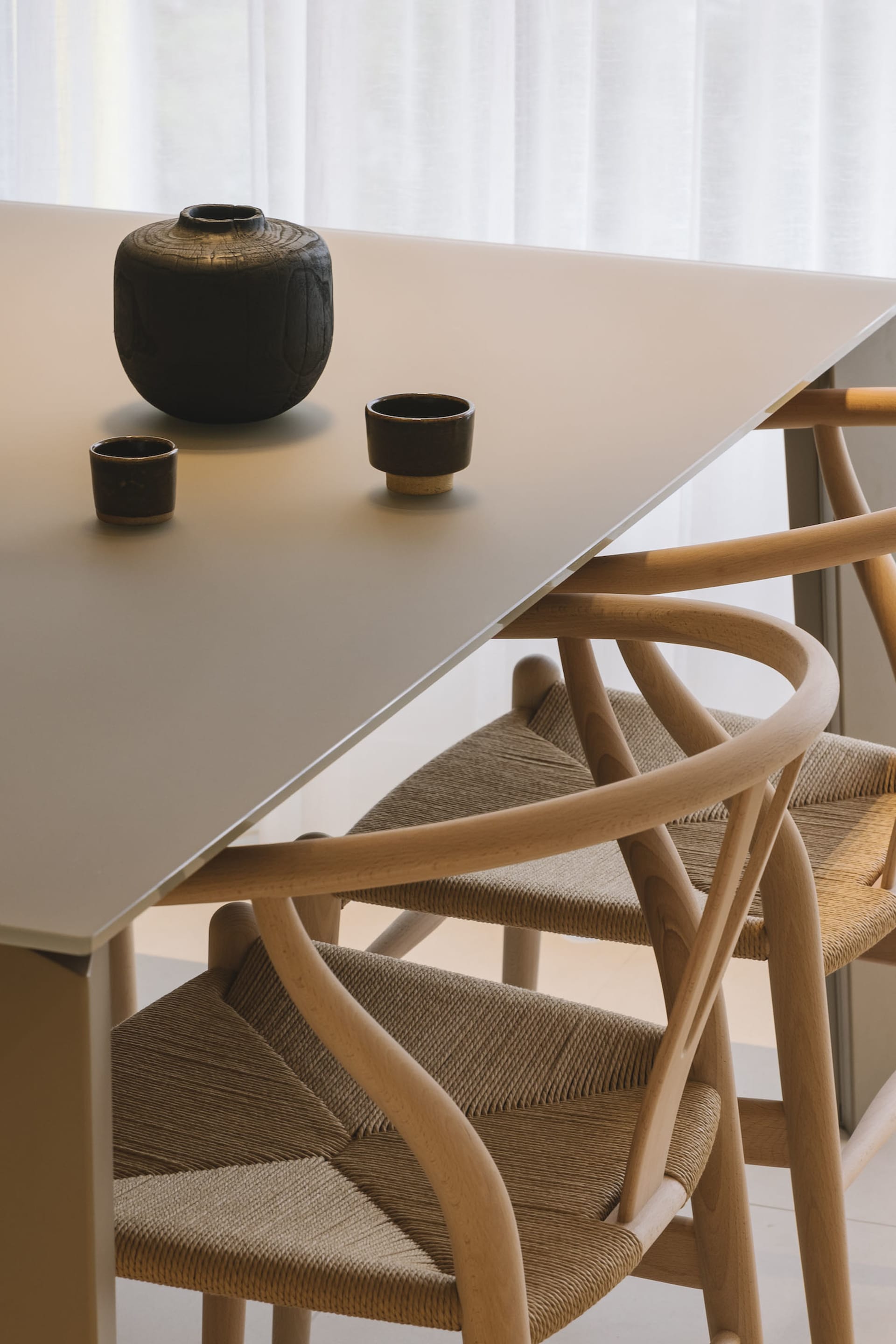 A modern dining room with a sleek white table, wooden chairs, and metal accents.