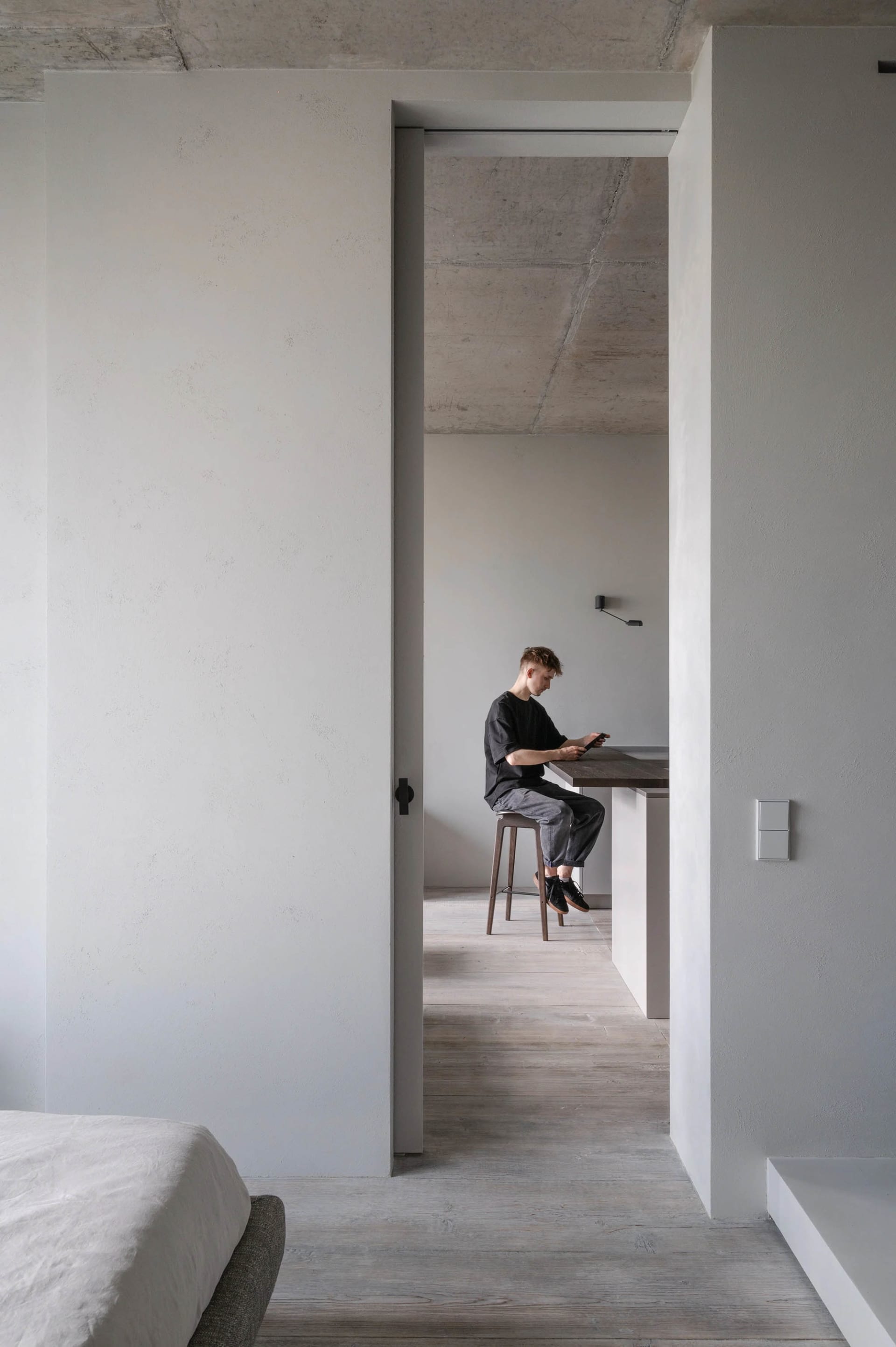 A minimalist residential space featuring industrial-style concrete, wood, and metal finishes.