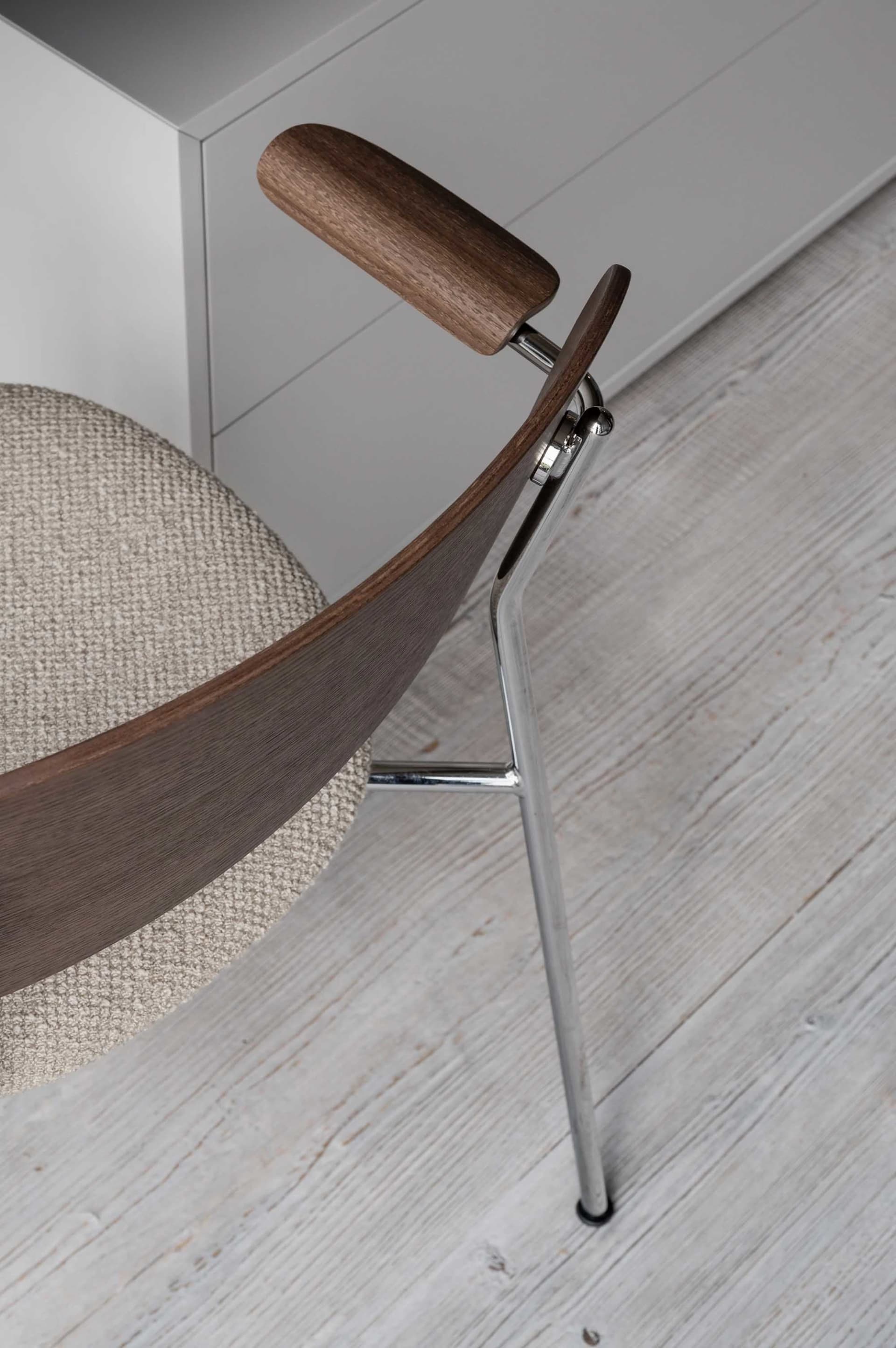 A modern chair with wooden arms and metal legs.
