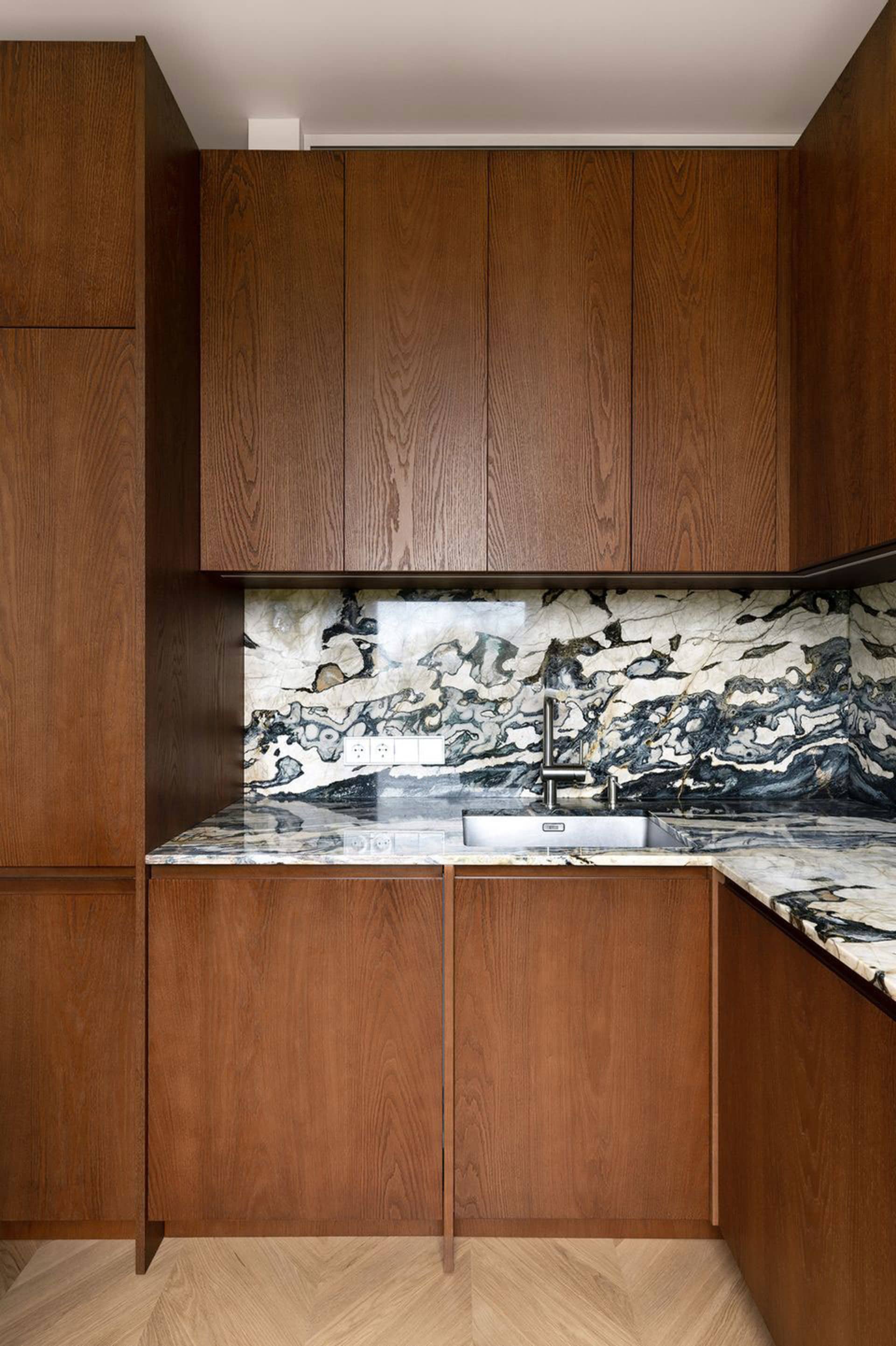 Modern minimalist kitchen featuring a luxurious marble countertop and backsplash.