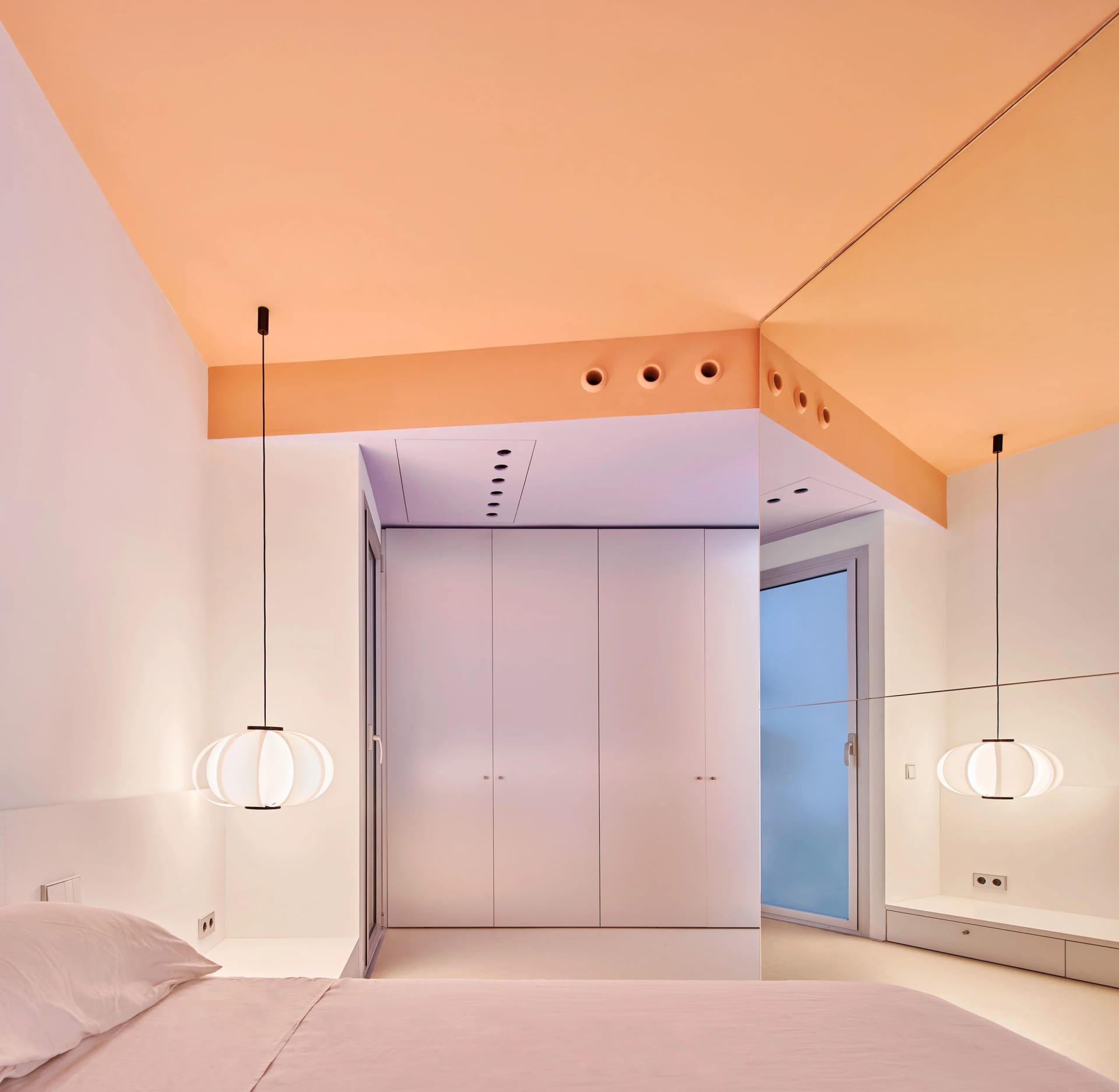 A minimalist bedroom with white walls and a concrete floor, featuring modern lighting and clean lines.