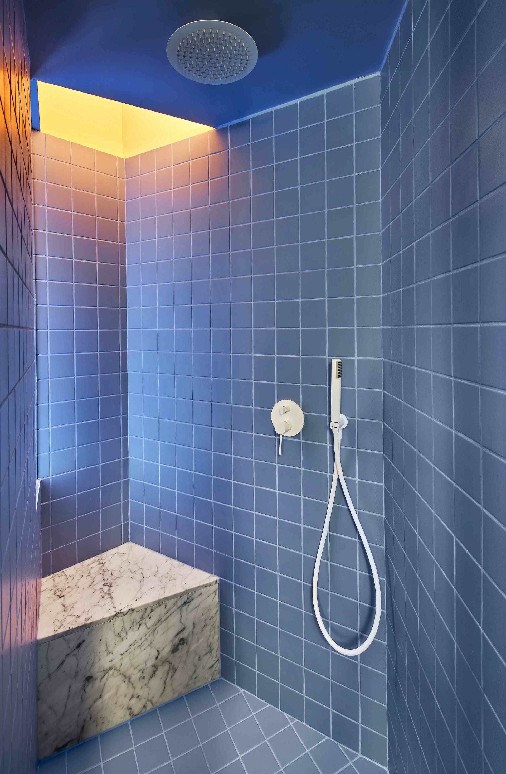 A minimalist bathroom with blue tiles and a marble seat