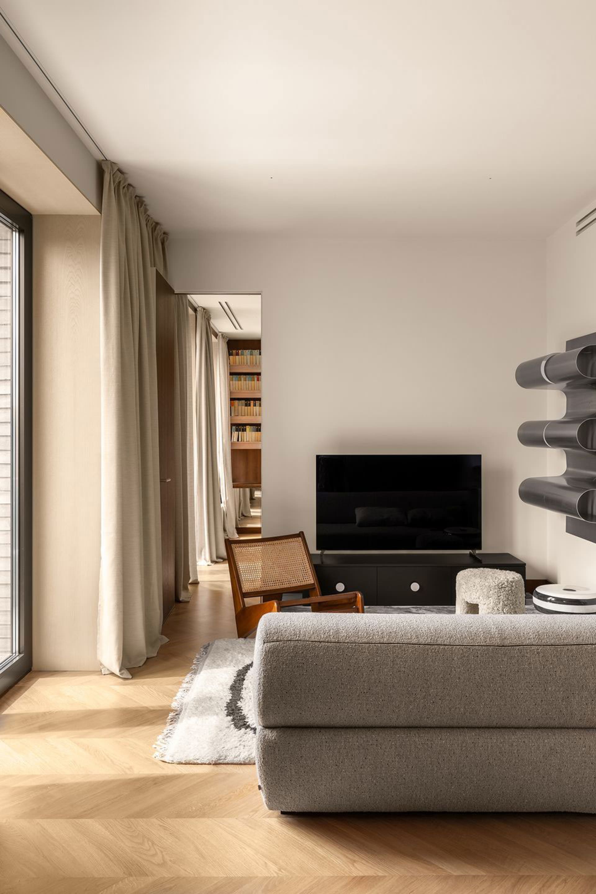 A modern minimalist living room featuring a gray sofa, wooden floor, and metal lighting fixture.