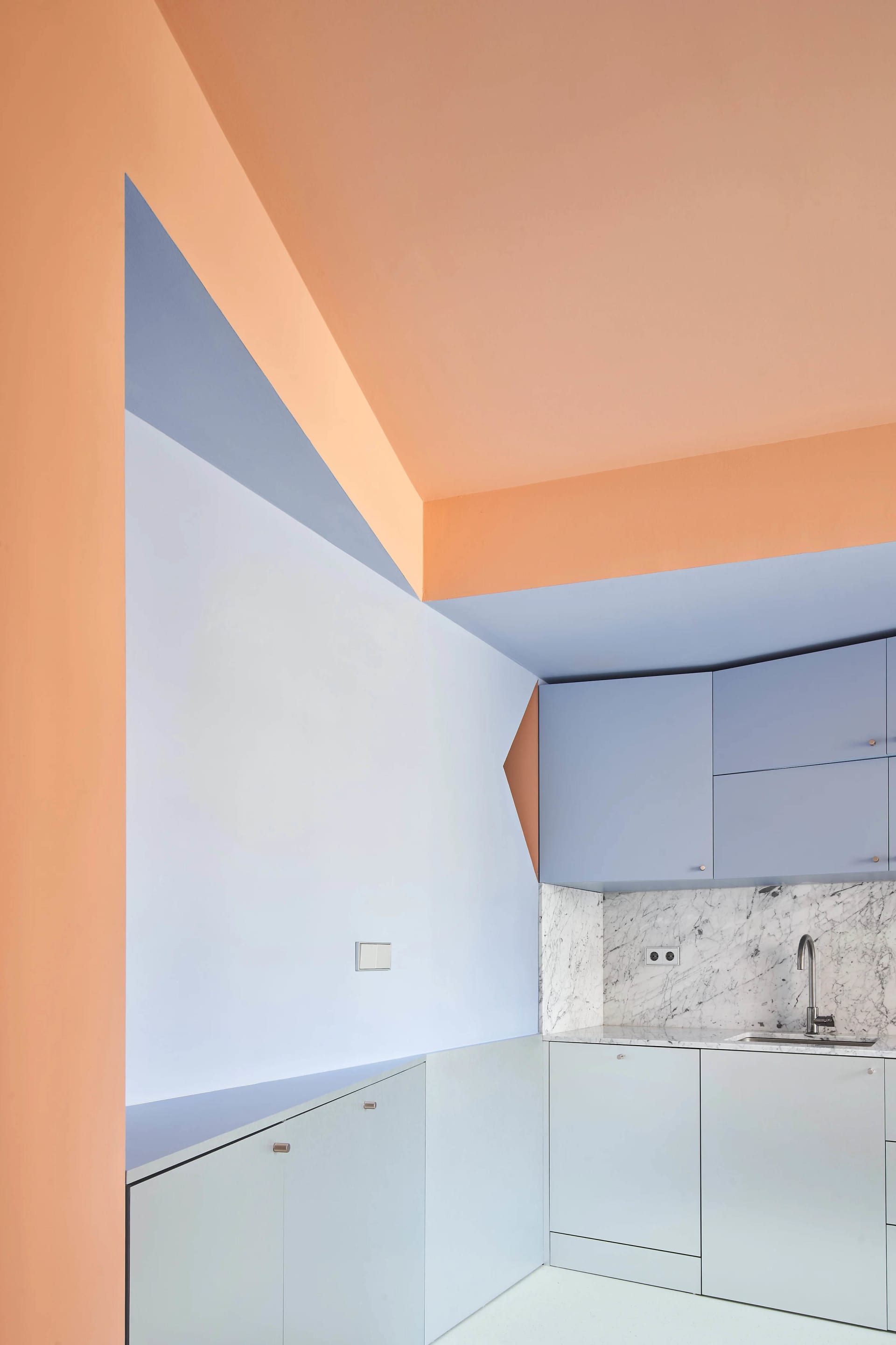 A modern kitchen with glass walls, white cabinets, and a marble countertop.