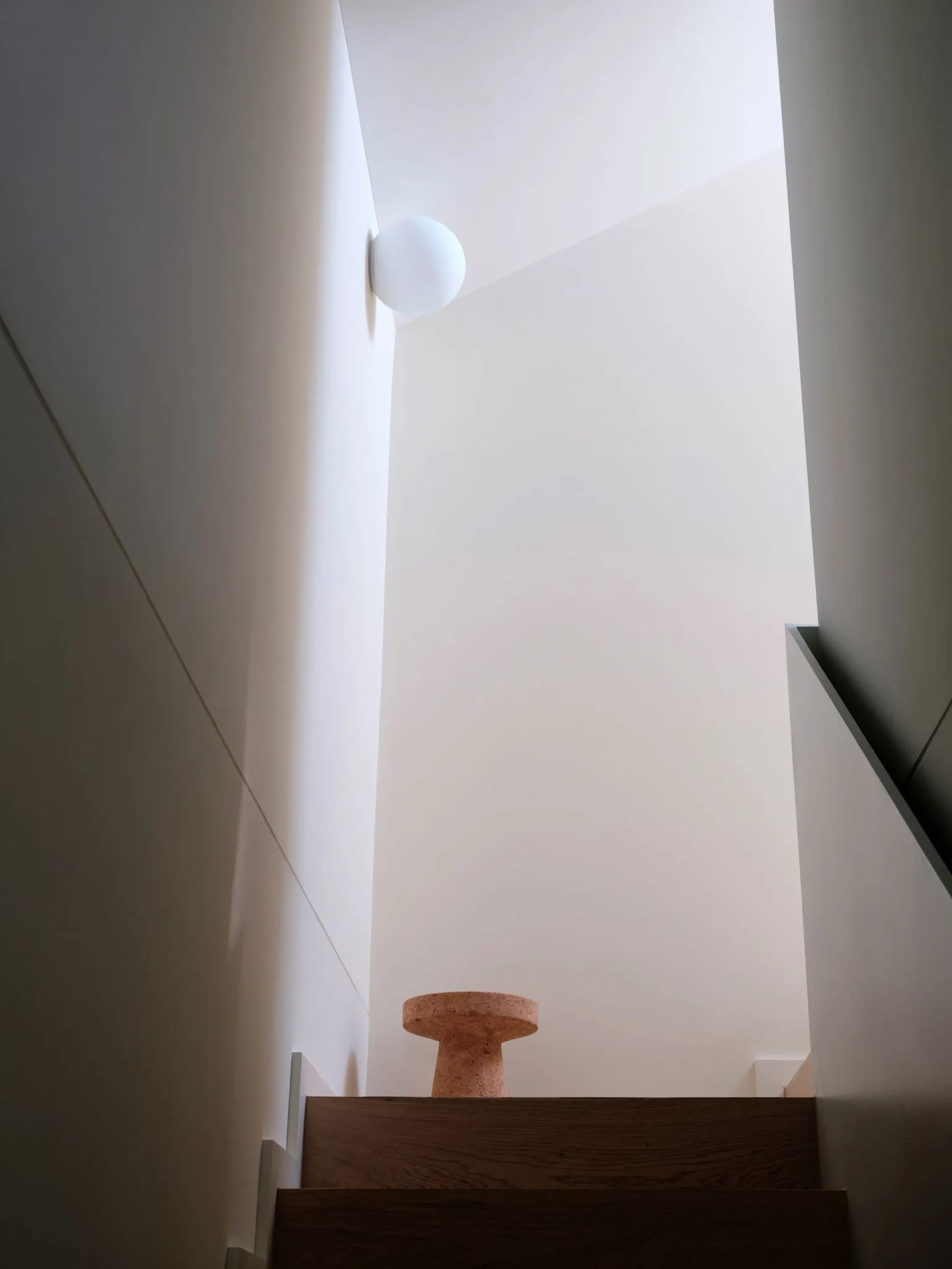 Minimalist interior design featuring a wooden staircase with modern lighting.