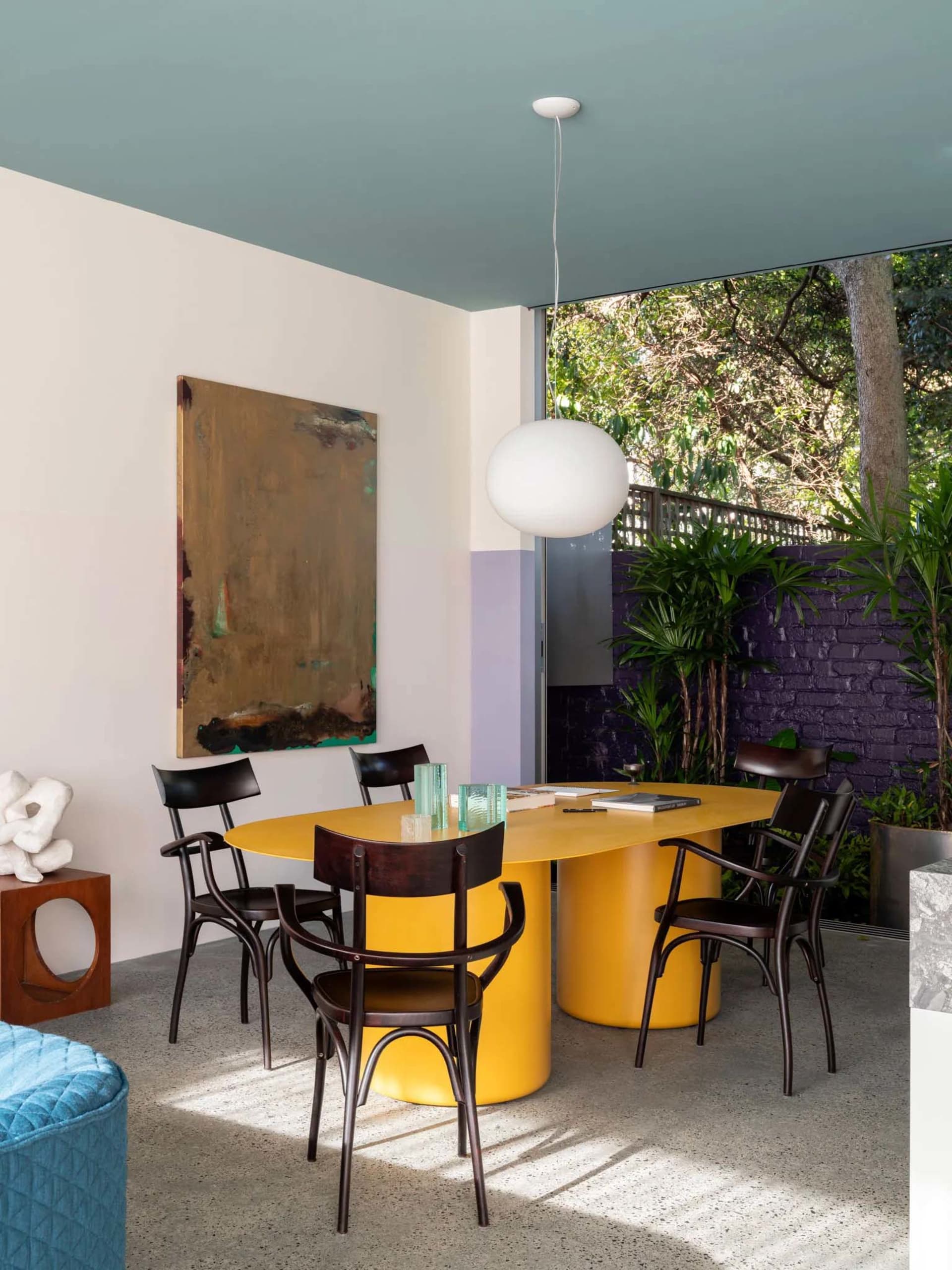 Modern, stylish dining room with a yellow metal dining table and black chairs.