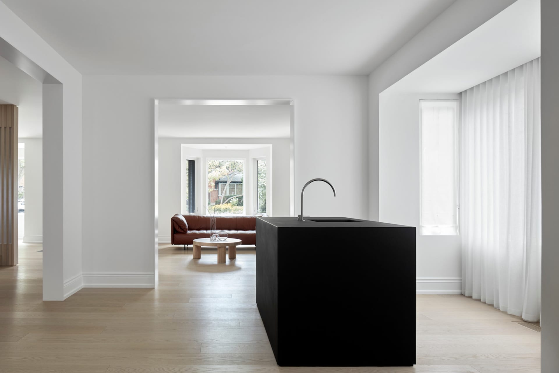 Modern interior design featuring a black kitchen island with a white countertop, contrasting light-colored wood floors, and a