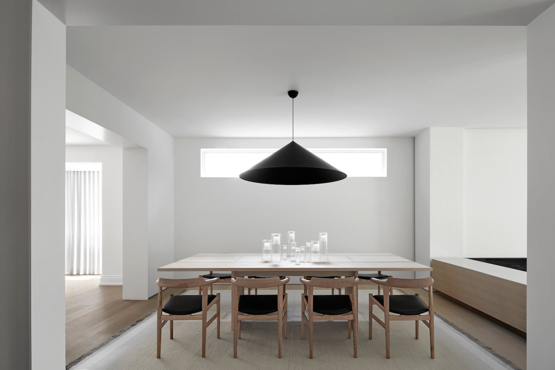 A modern minimalist dining room with a wooden dining table and chairs.