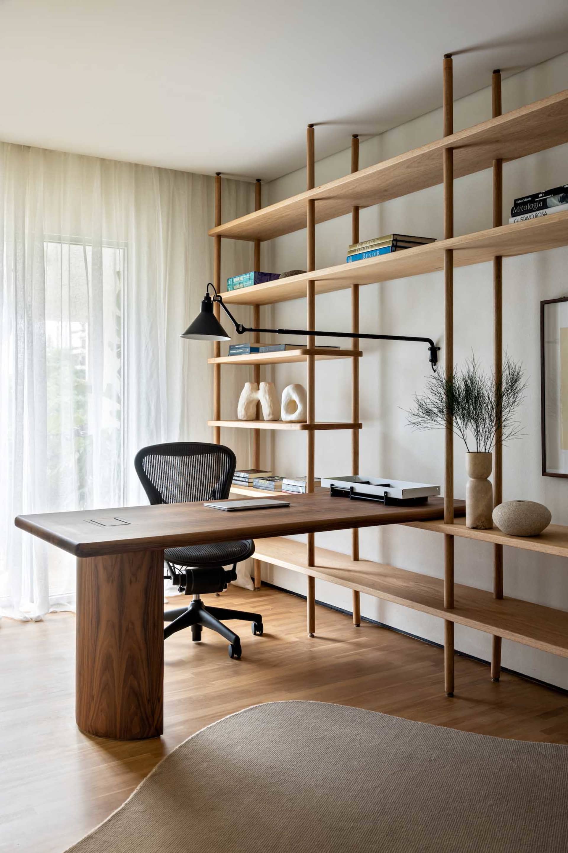 A modern minimalistic home office featuring a wooden desk and bookshelf.
