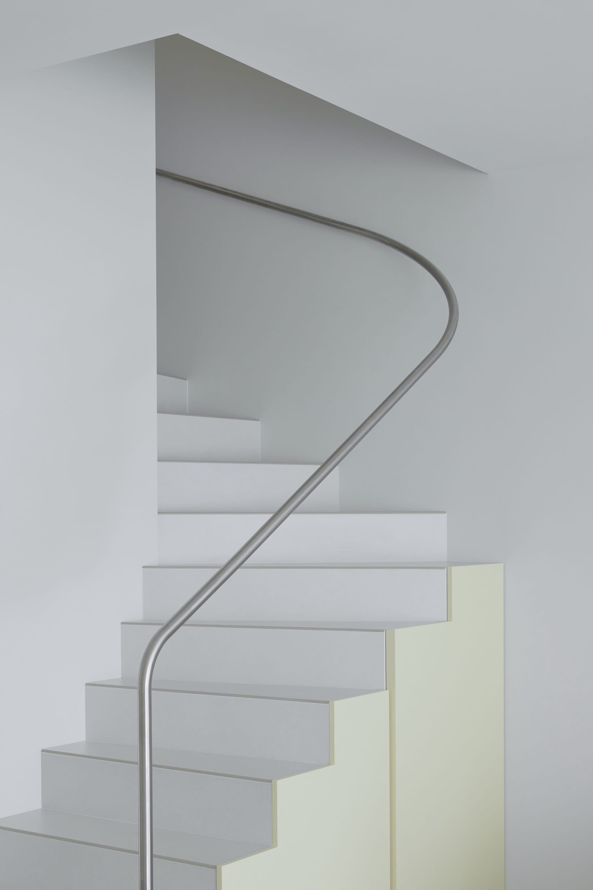 A modern white staircase with a steel handrail