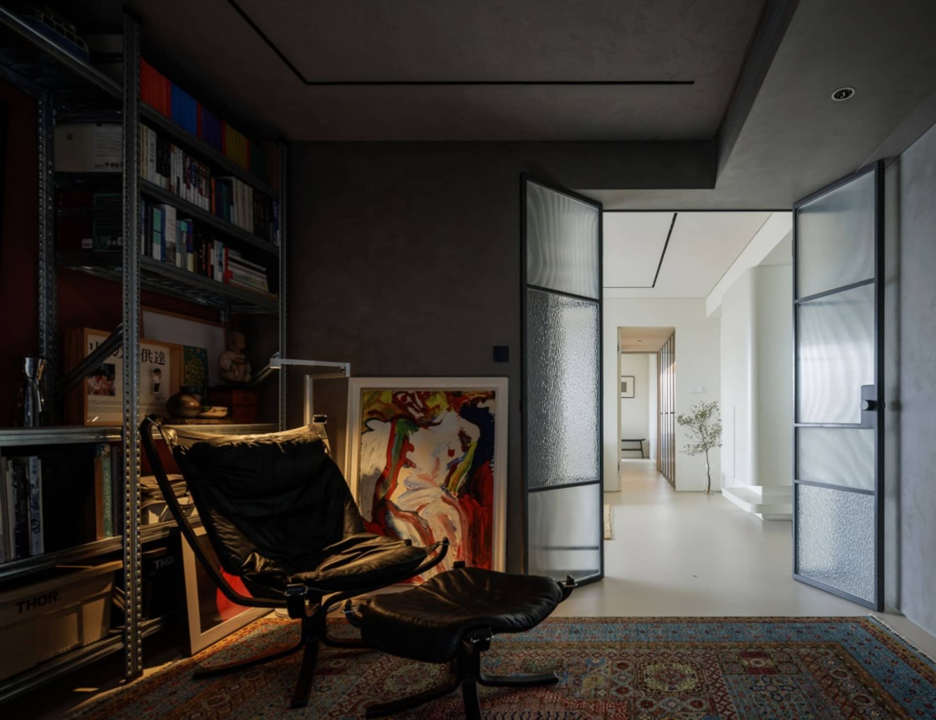 A contemporary living room with a black chair, rug, and colorful painting.