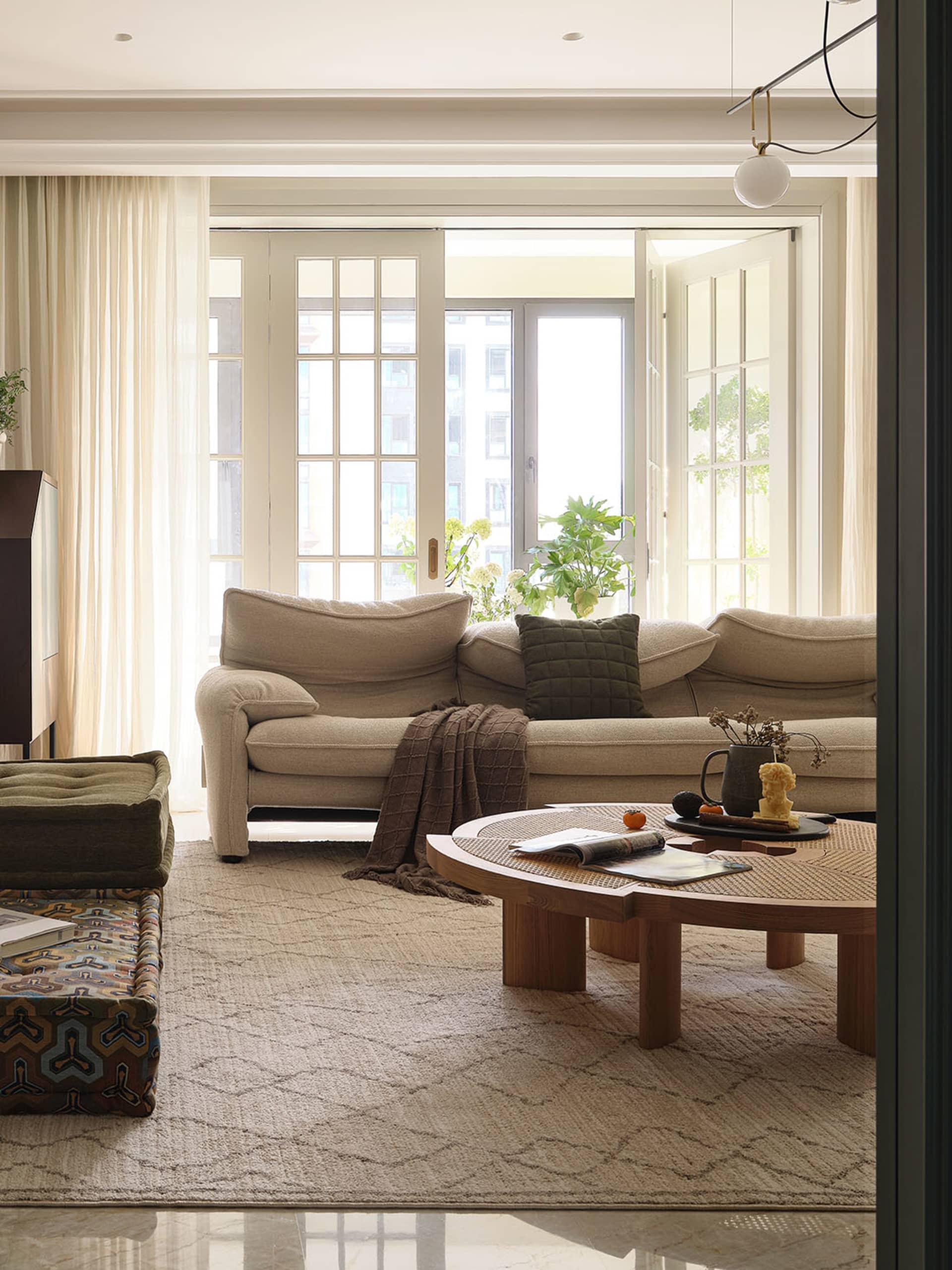 A minimalist living room featuring neutral-toned fabrics, wood accents, and large windows allowing natural light to flood the