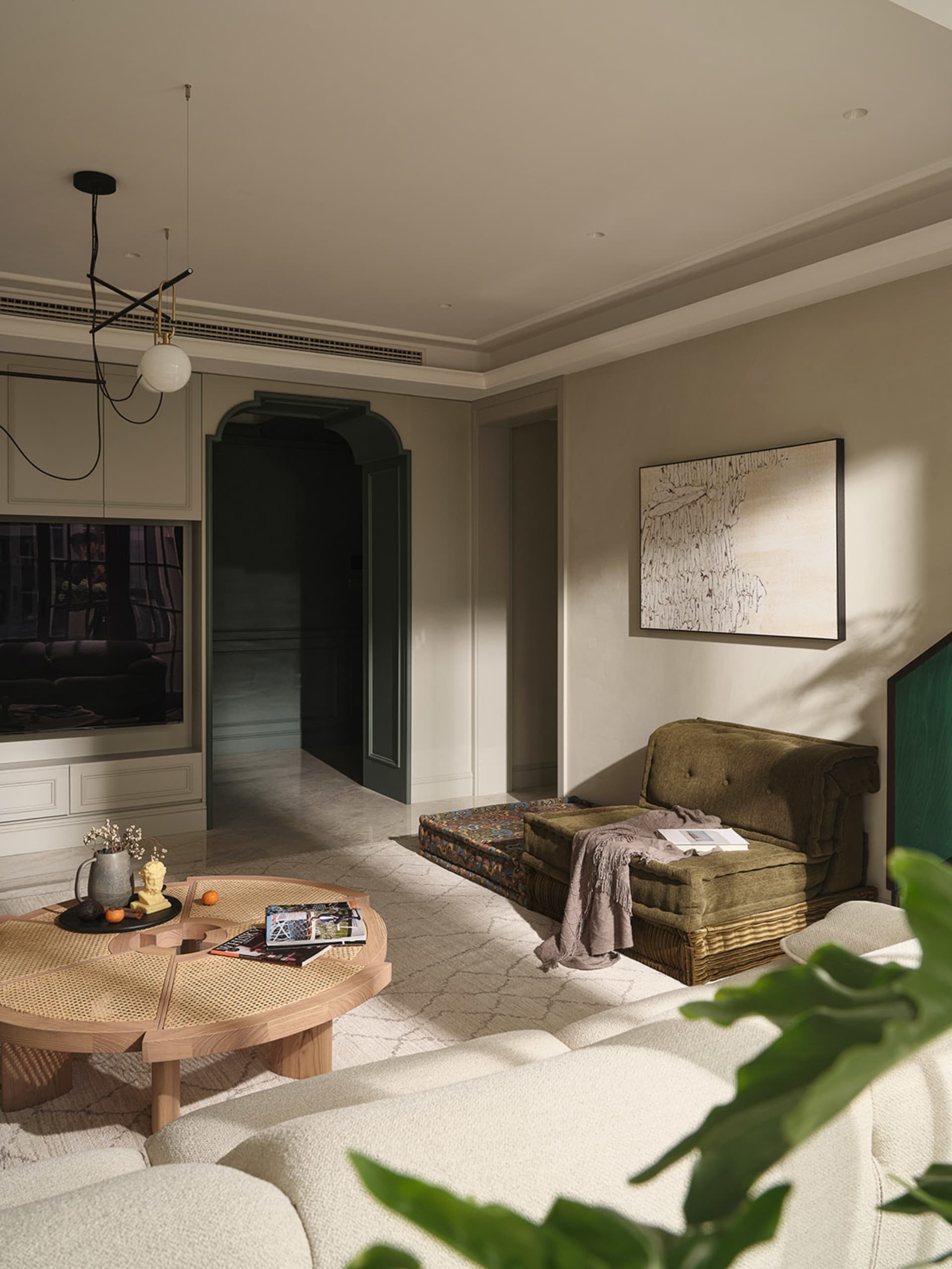A minimalist living room with taupe-colored furniture, a rattan side table, and a white couch.