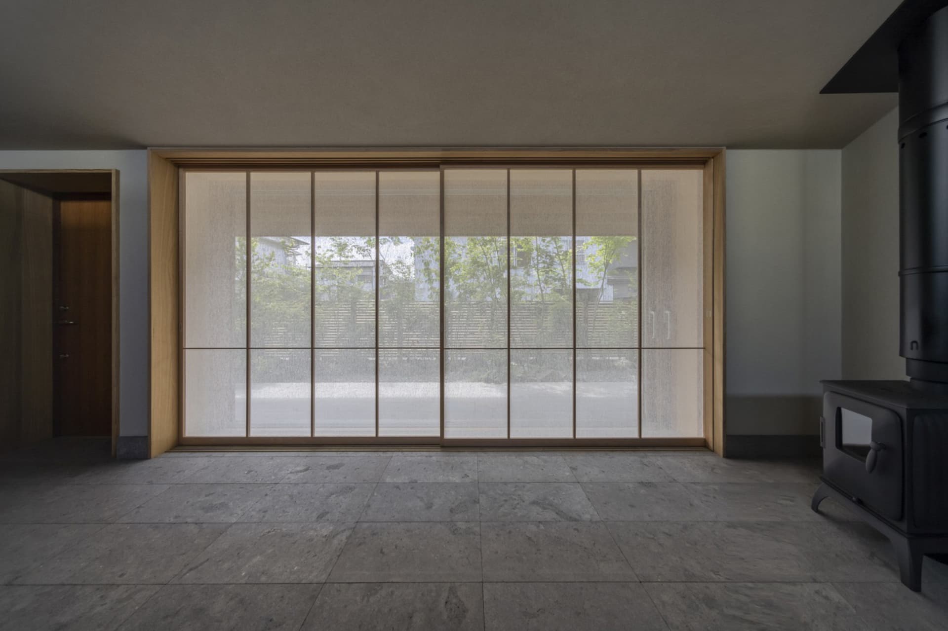 Modern minimalist living room with large window and wooden floor.