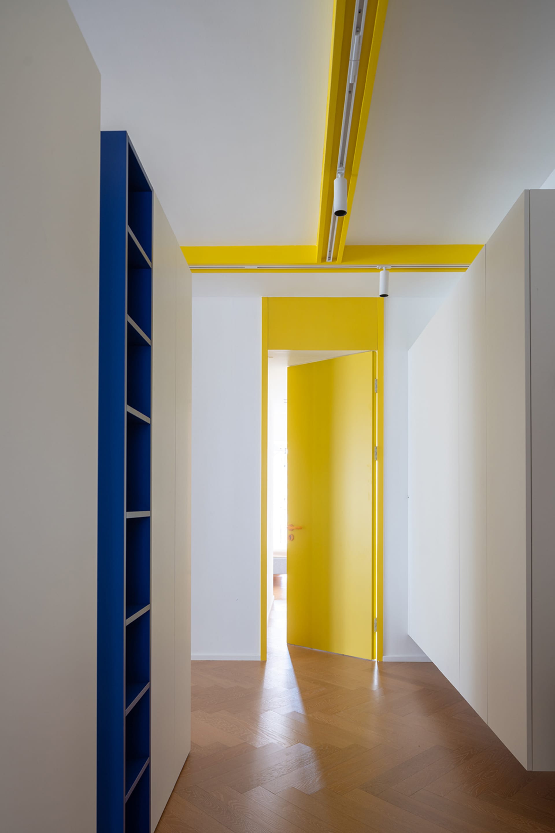 Modern space with blue shelves, yellow accents, and wooden flooring.