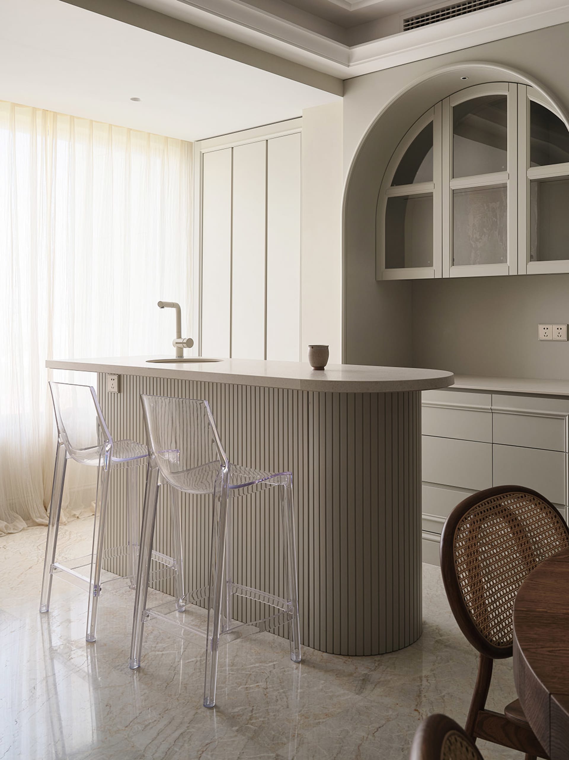 Modern kitchen with concrete island, bar stools, and sleek design.