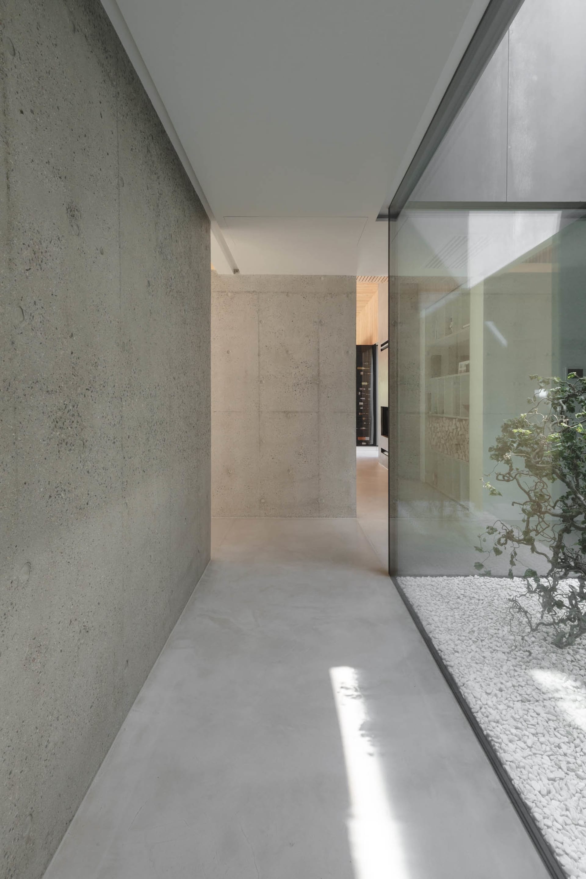 Concrete entrance hall with glass wall and rock garden.