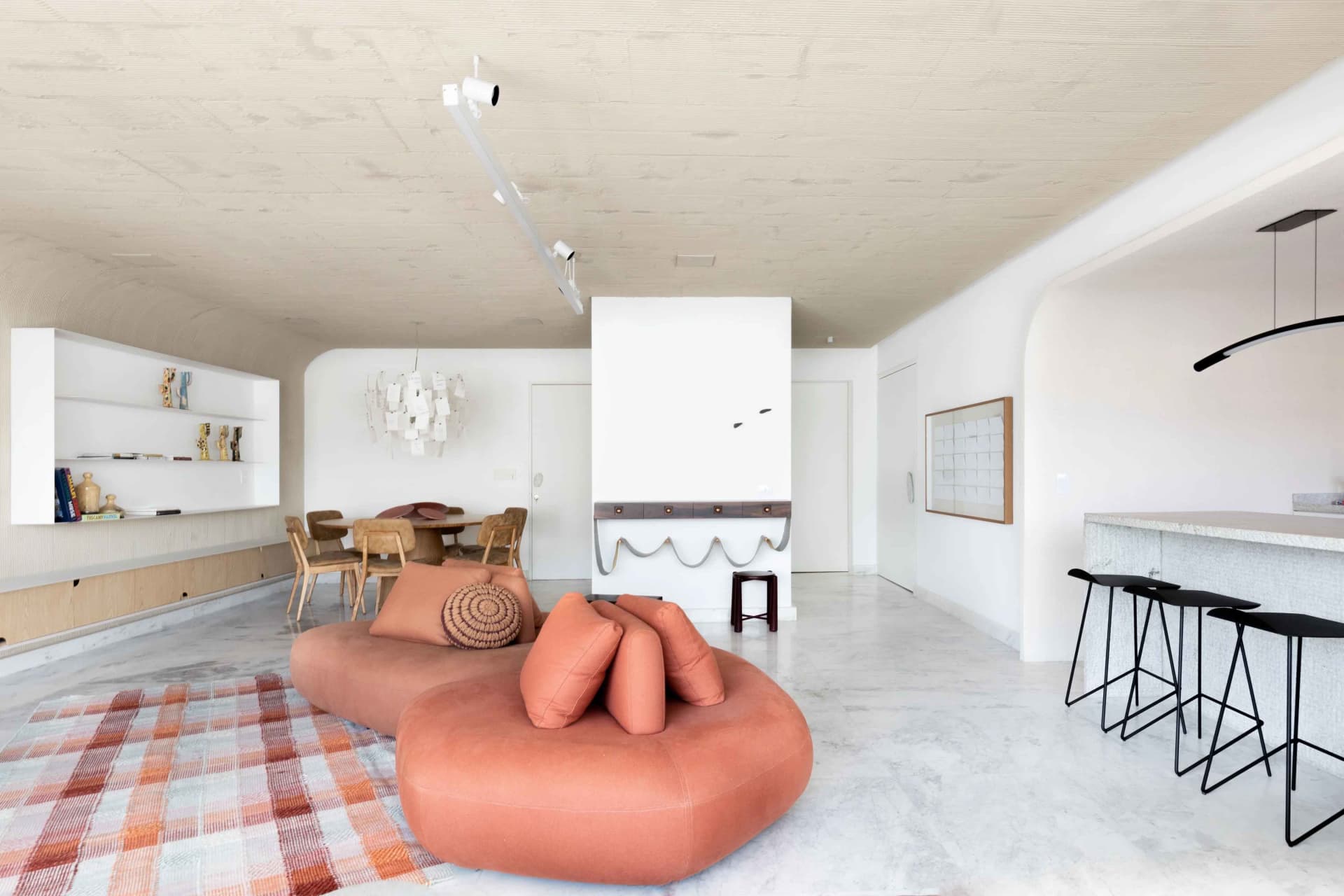 A modern living space featuring a comfortable lounger, high stools, and a sleek bar counter.