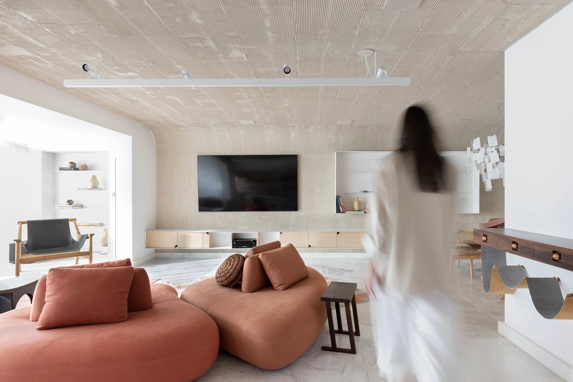 A modern living room featuring soft, comfortable furniture and a concrete ceiling and walls.