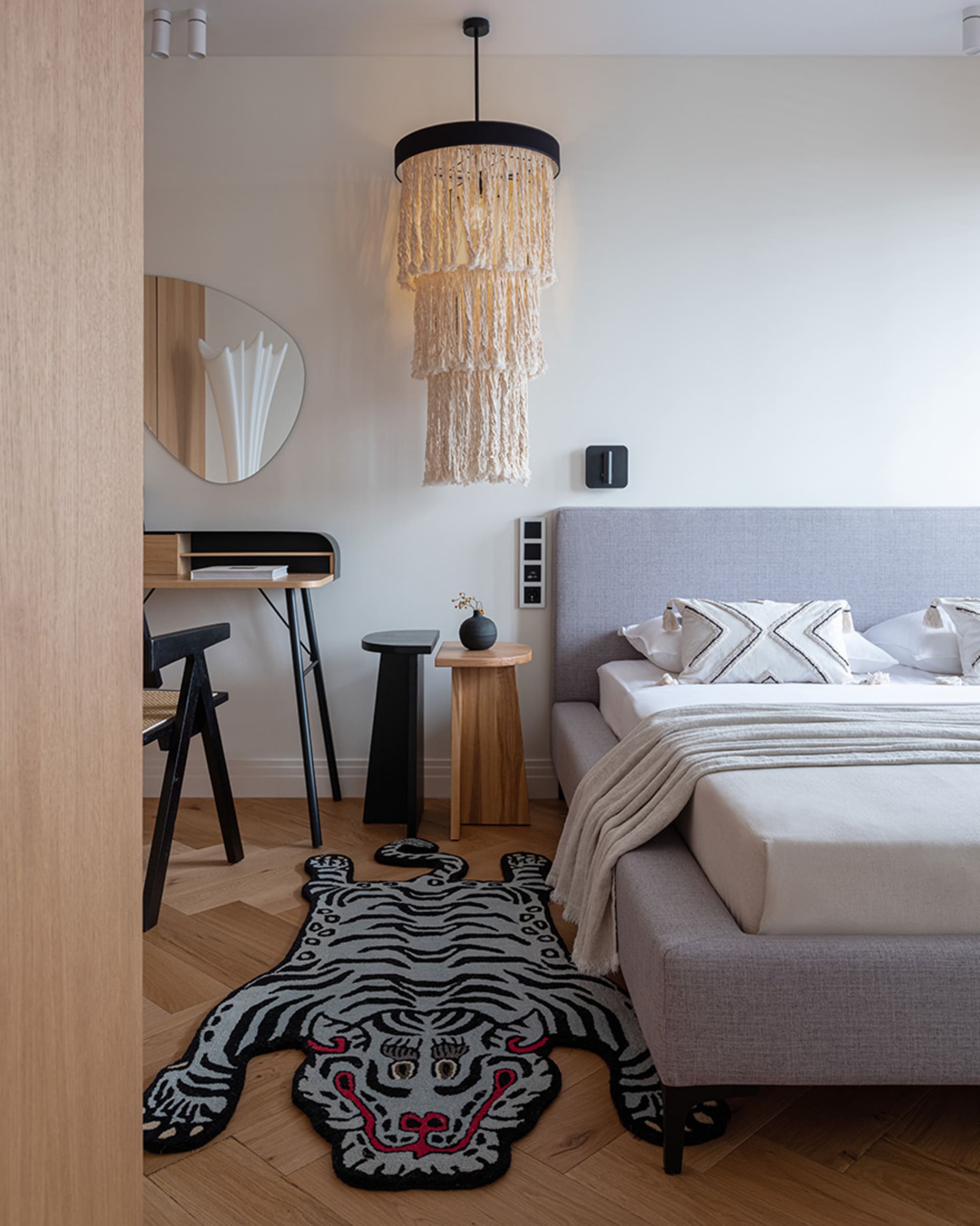 A modern, minimalist bedroom with a draped bed, a tiger-patterned rug, and a modern bed.