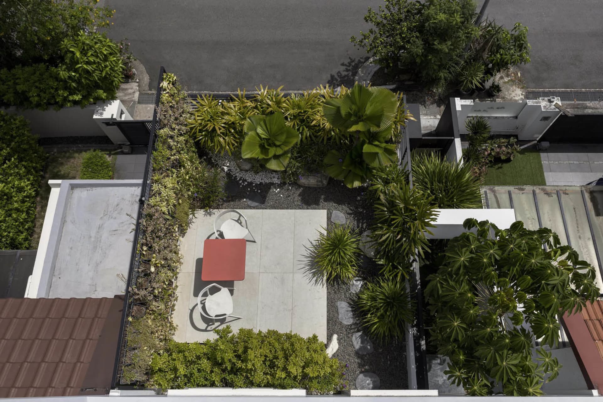 A modern design featuring concrete patio, rocks, and lush green plants on a rooftop or courtyard.