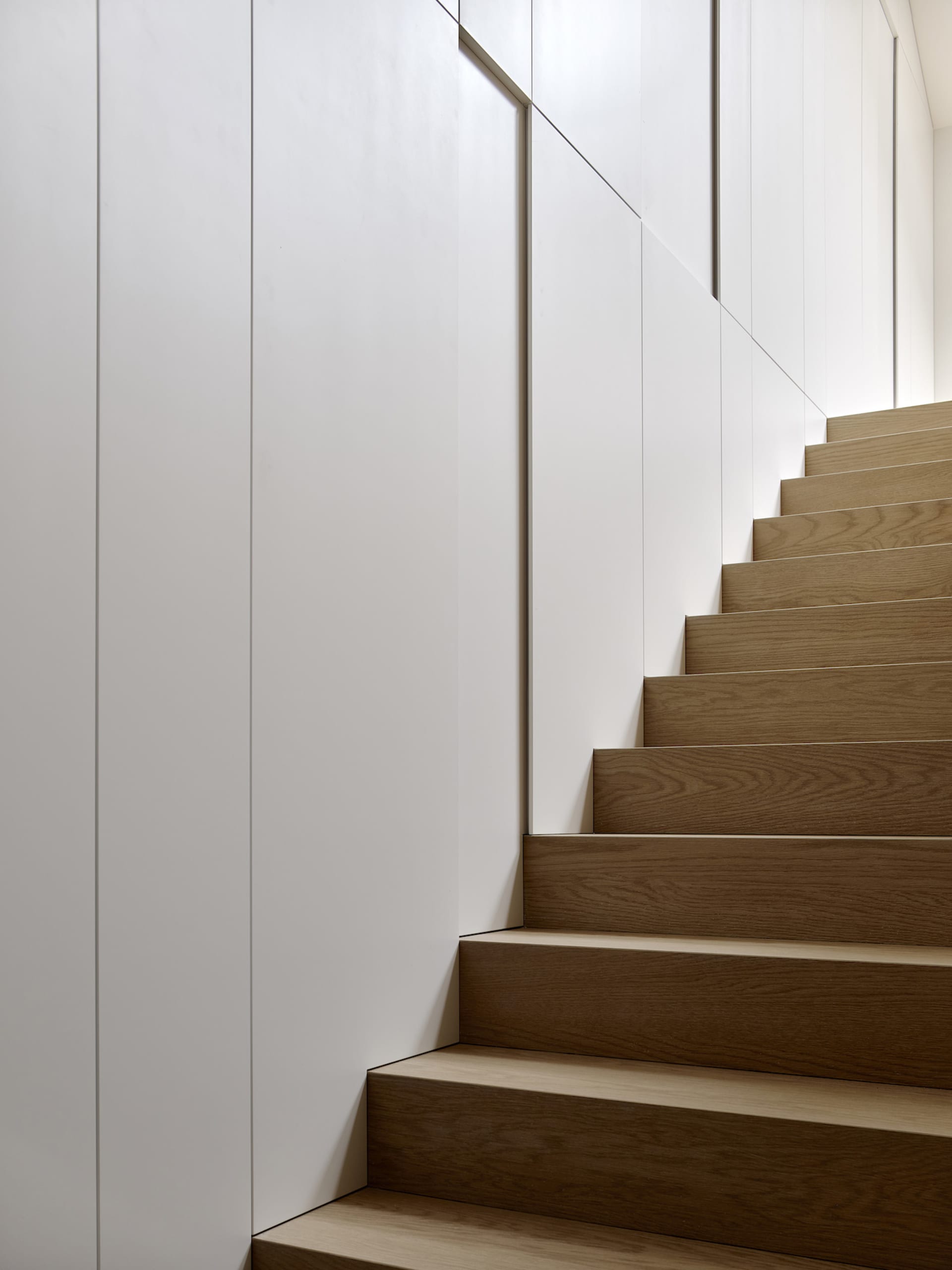 A modern staircase with wooden steps and metallic railings.