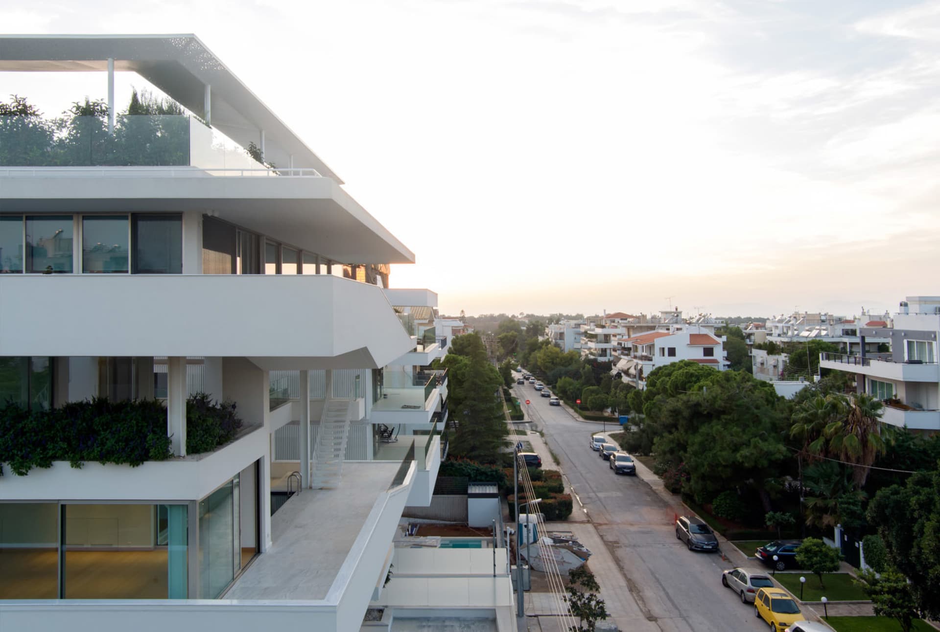 Modern apartment building with glass and concrete exteriors and white balconies.