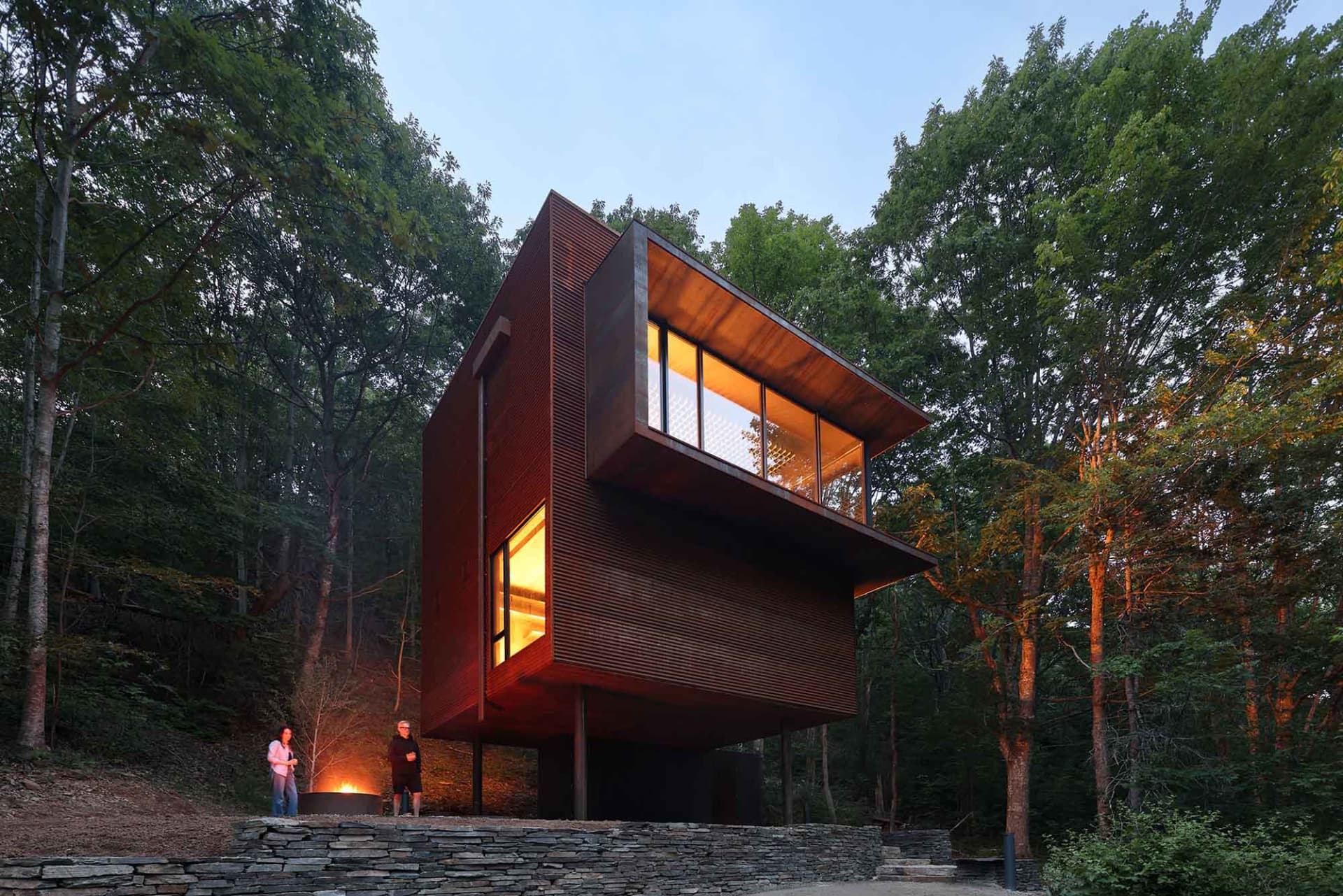 A modern residential interior with a wooden exterior on a forested hillside.