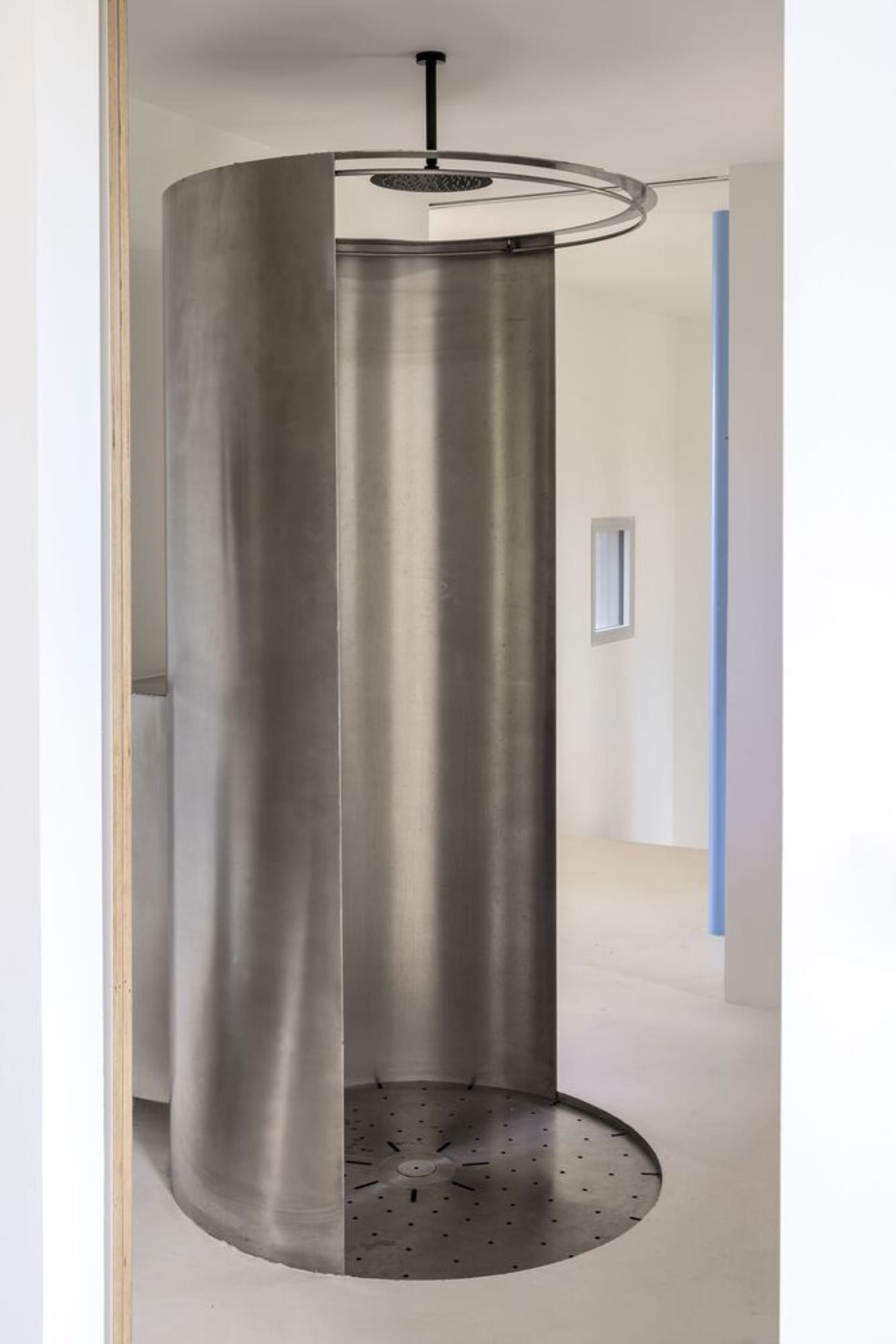 A minimalist, industrial-style bathroom shower with a metallic finish and geometric design elements.