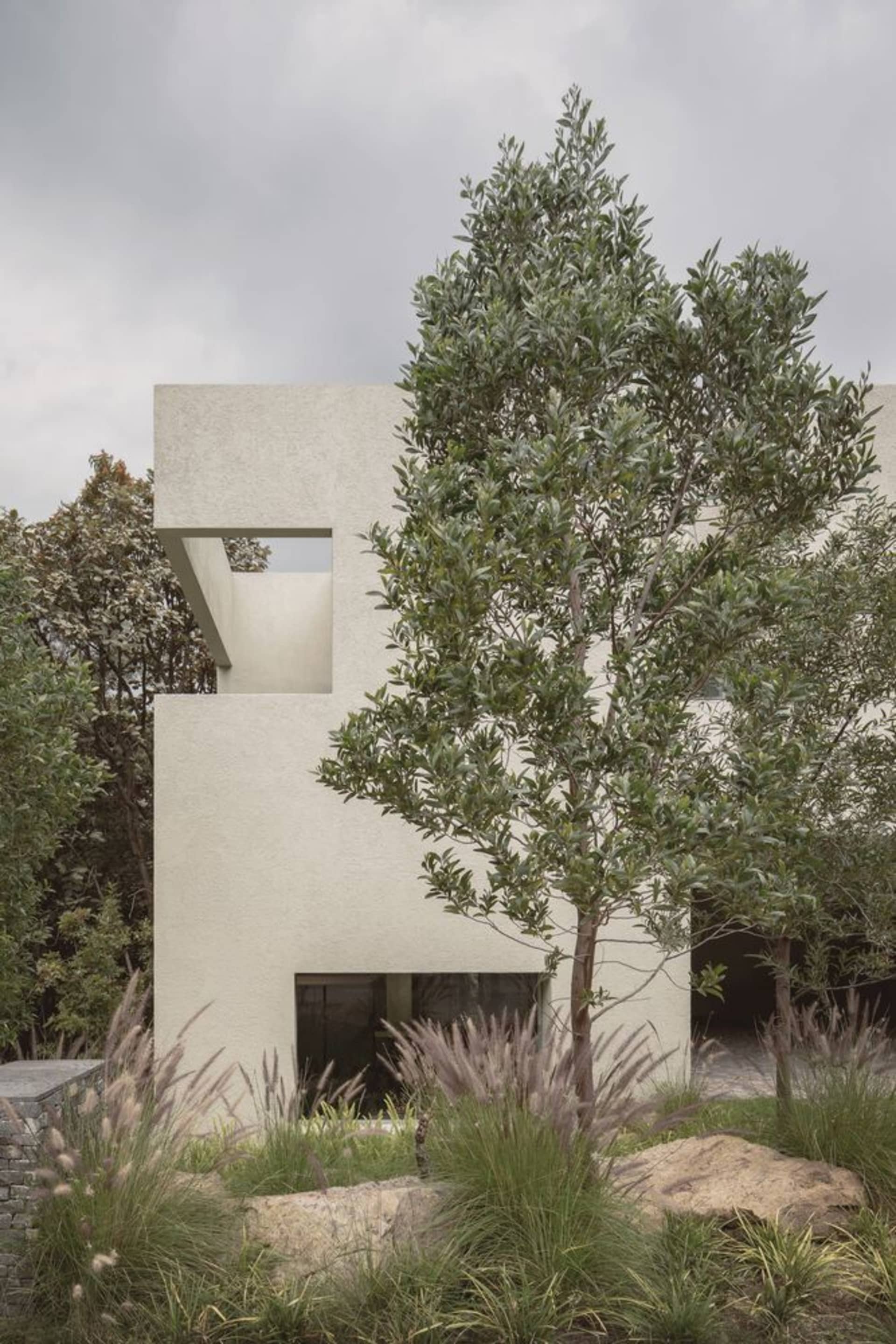 Modern minimalist house with concrete exterior and greenery.