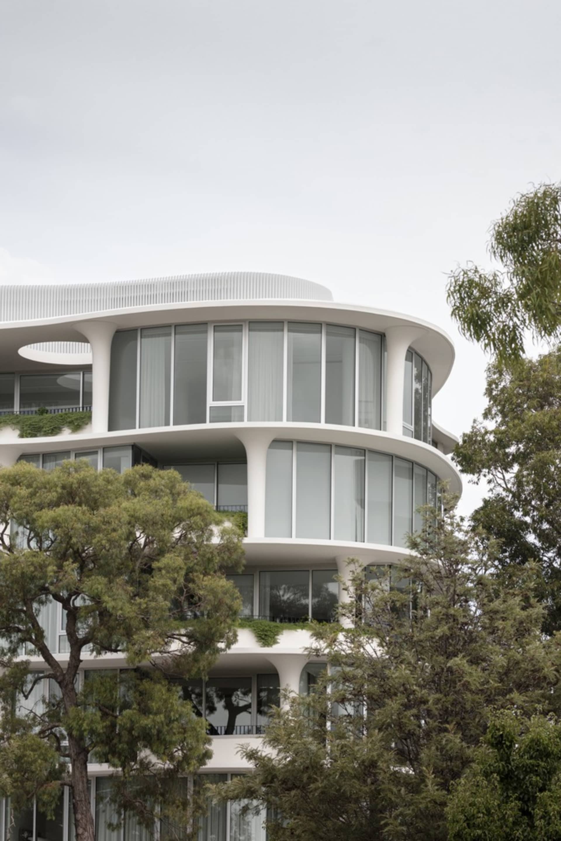 A modern residential building with glass walls and a white concrete facade.