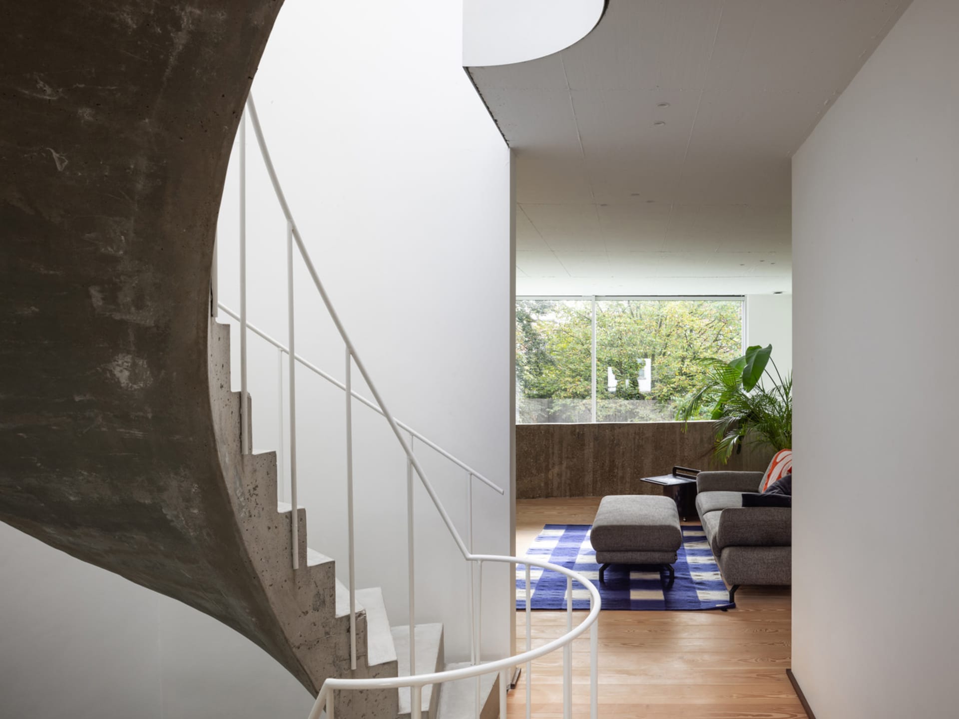 A modern interior living room featuring a concrete staircase and steel elements.
