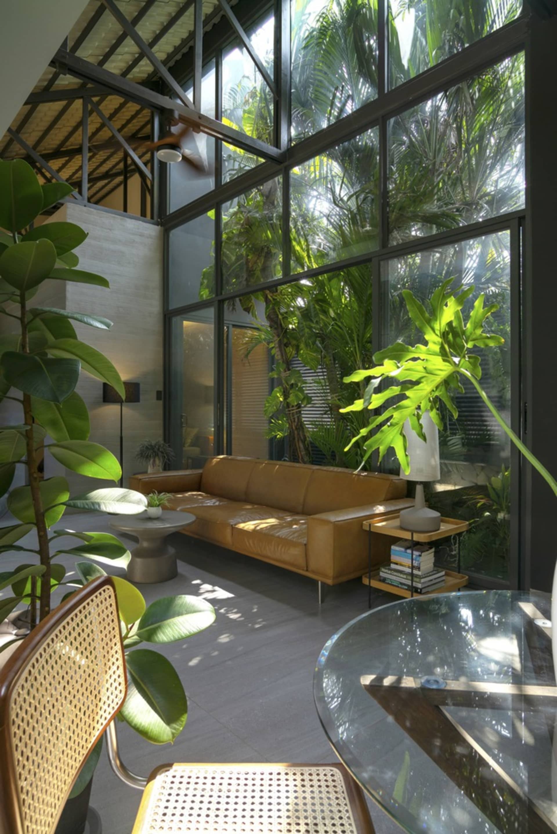 Modern minimalist living room featuring a brown leather sofa, green plants, and natural wood elements.