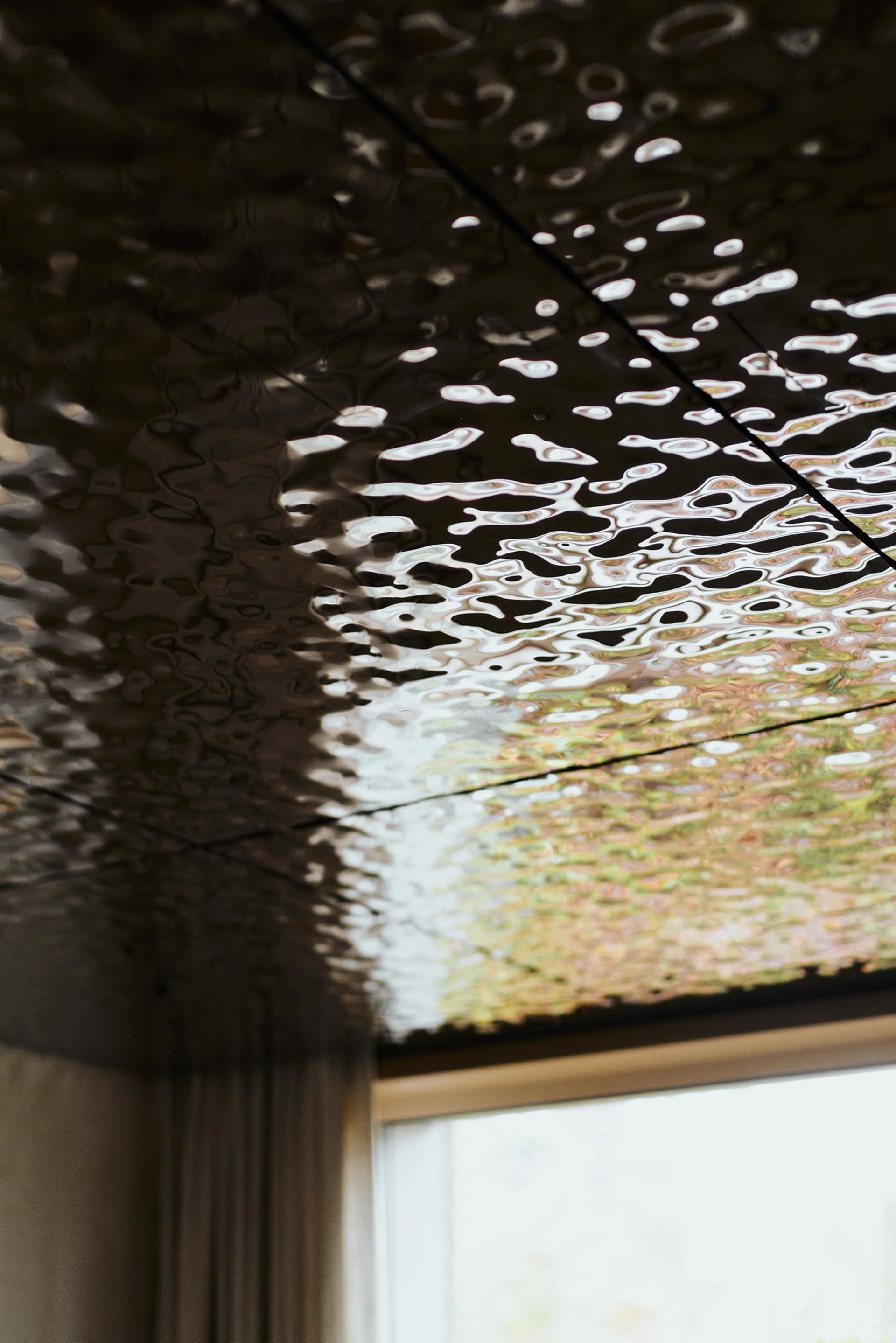 A textured ceiling reflecting a water surface with ripples and light effects.