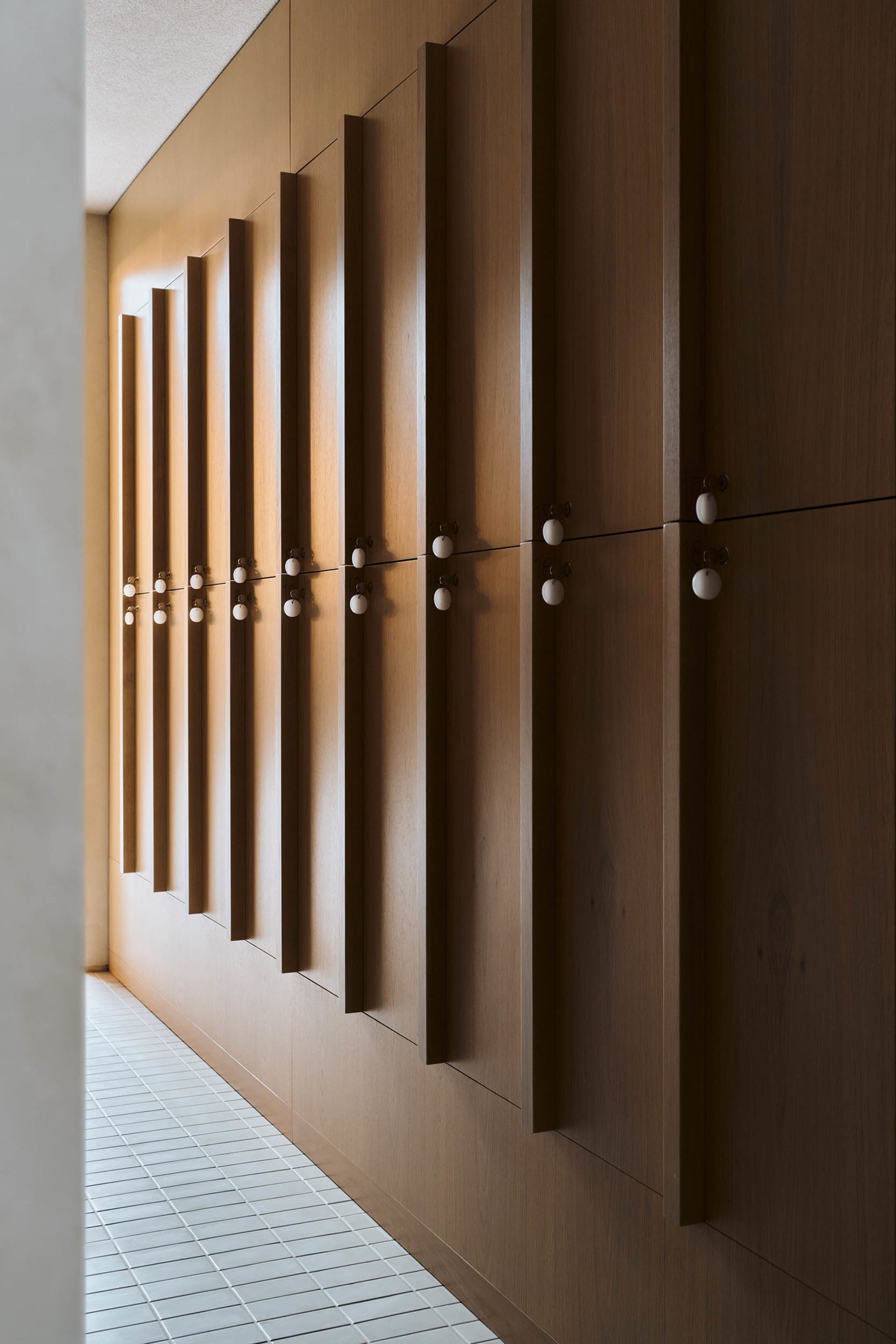 Modern lockers made of wood in a row on a tiled floor.