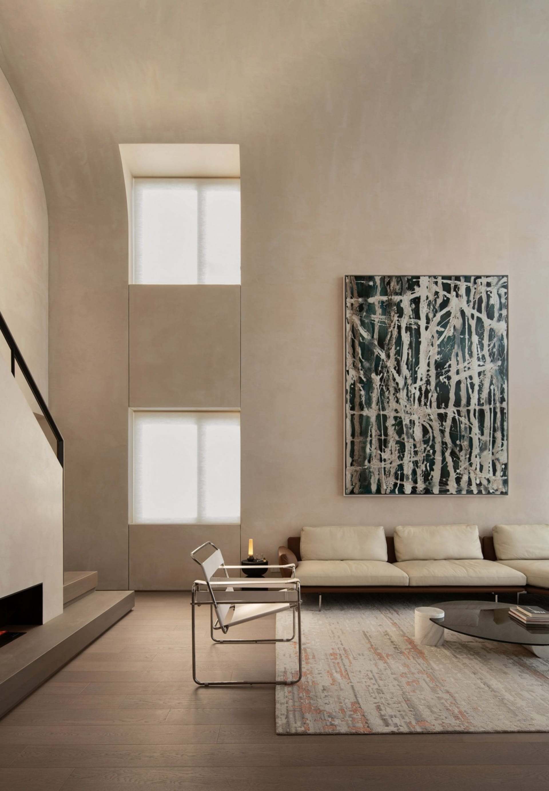 A minimalist living room with concrete walls, wooden floor, and a concrete fireplace.