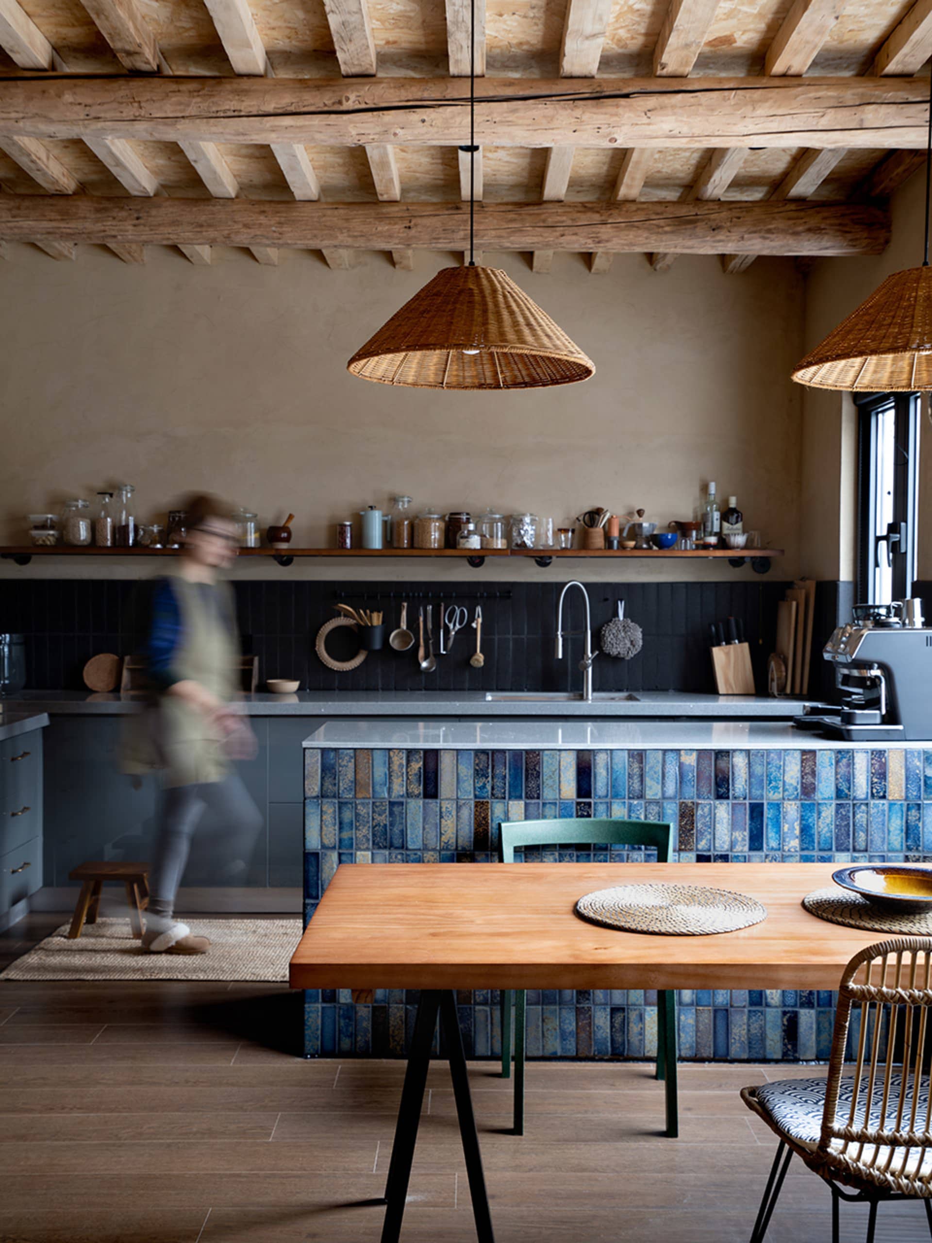 Modern kitchen interior with blue tiles and wooden elements, featuring a spacious dining area and a practical worktop.