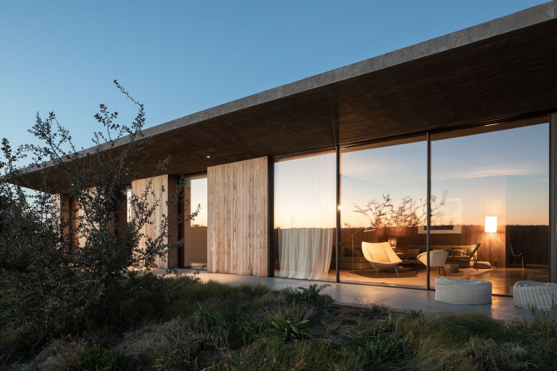 Modern residential exterior featuring glass walls and wooden elements.